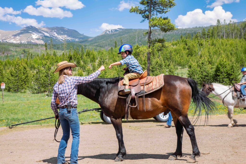 Wrangler fist-bumps young horseback rider