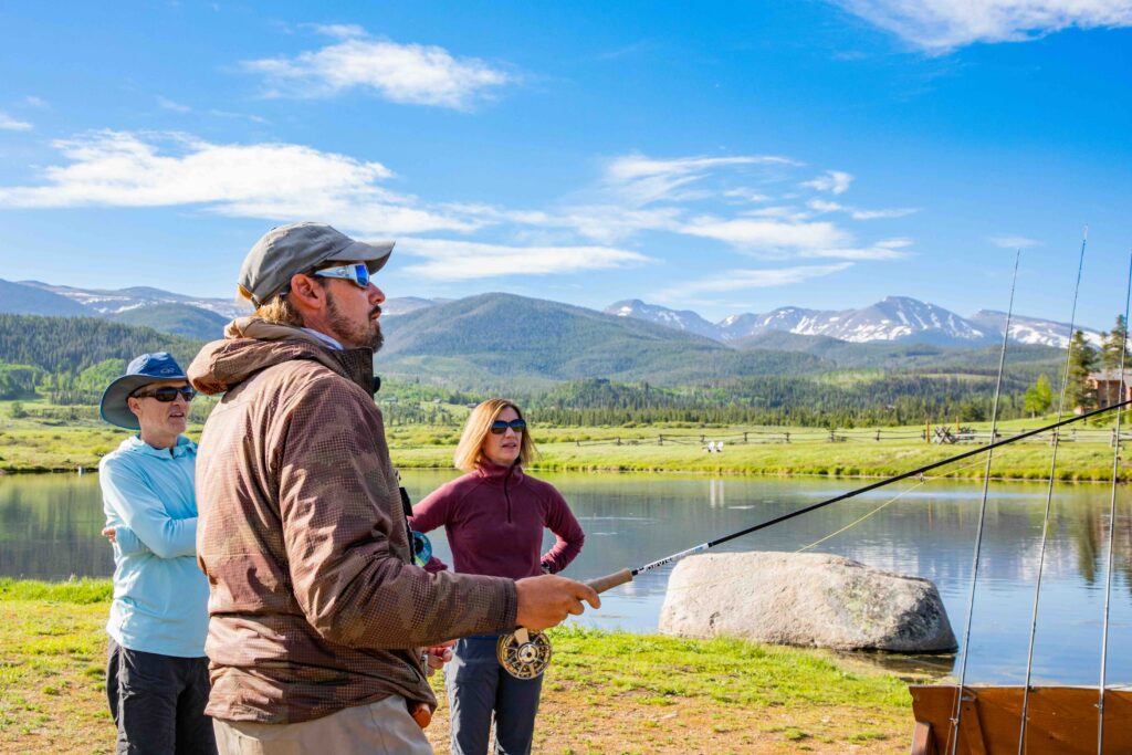 A fishing guide teaches two adults about fly fishing
