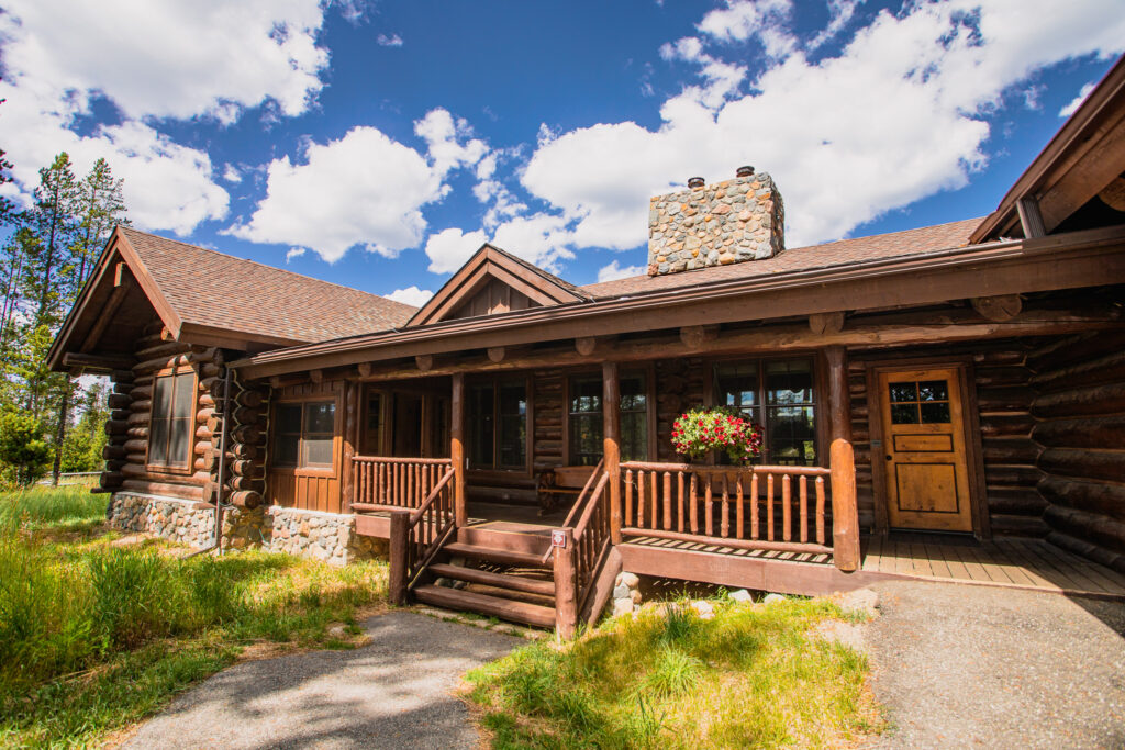 Blue Sky log cabin exterior with green grass and hanging planters and blue sky