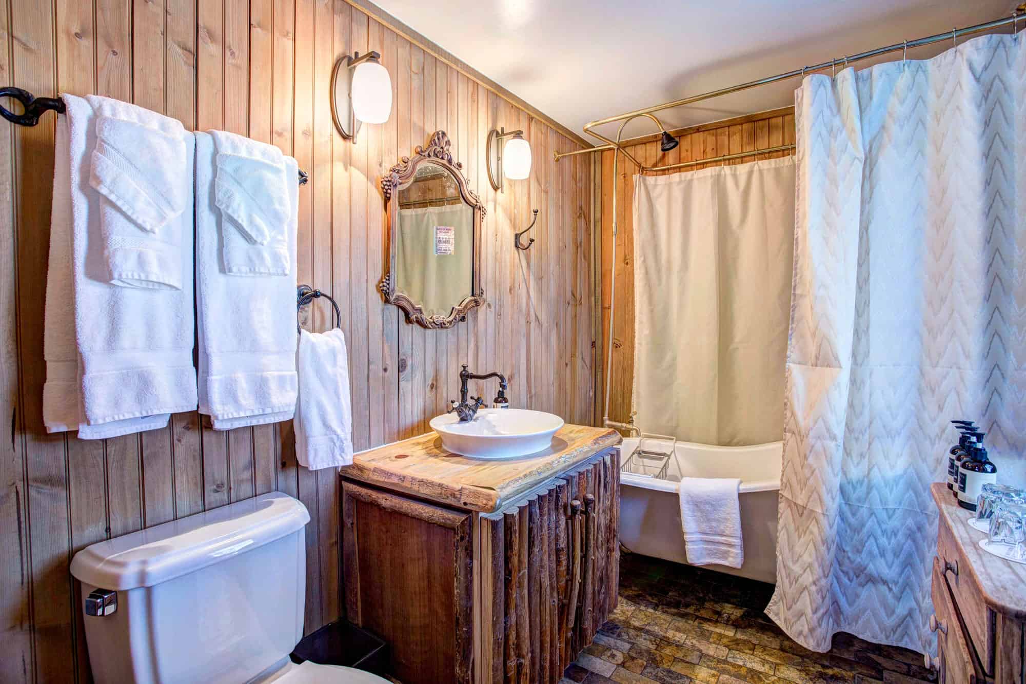 Rustic bathroom with wooden walls, vintage mirror, and cozy shower curtain.