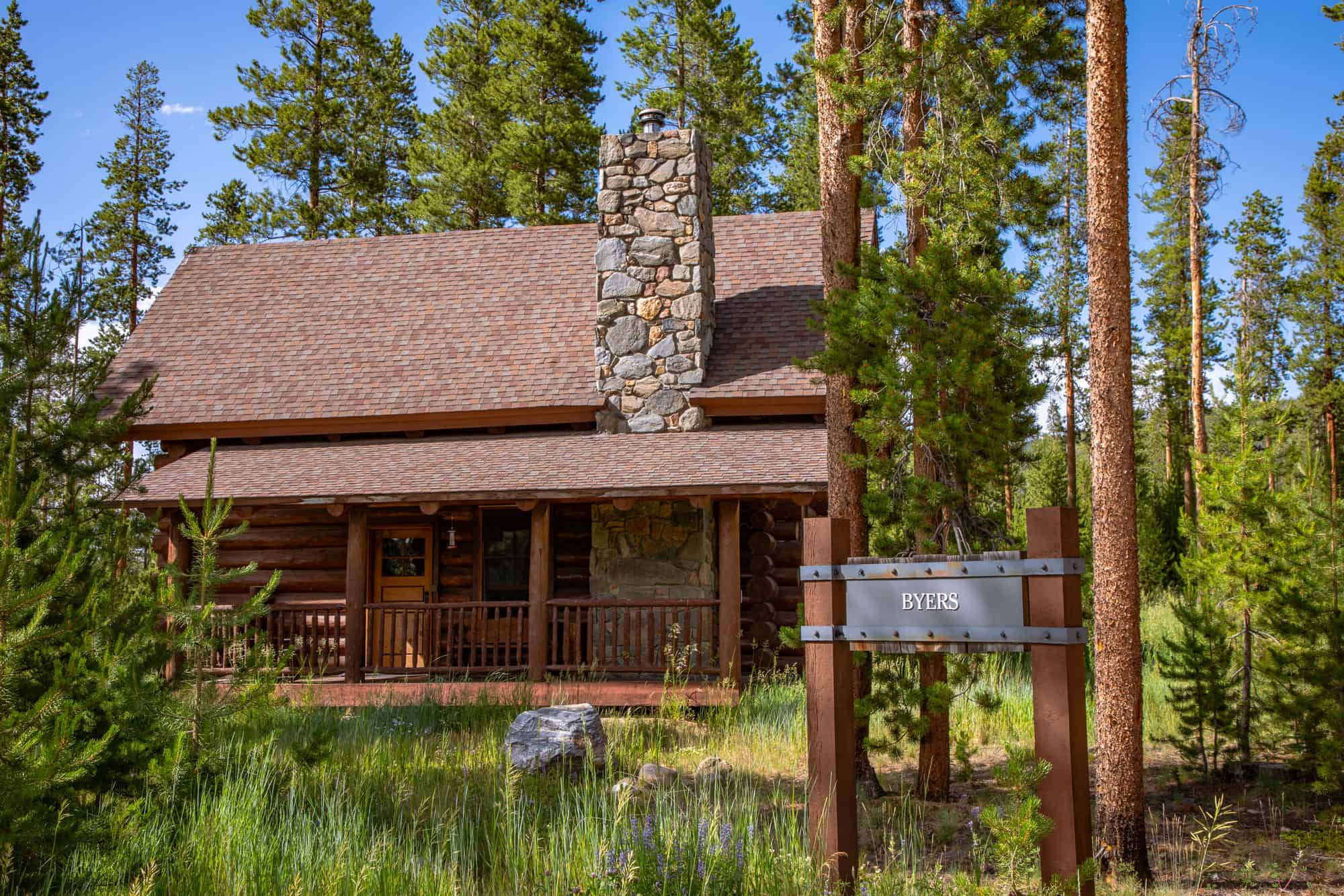 Cozy mountain cabin at Devil's Thumb Ranch surrounded by tall pine trees.