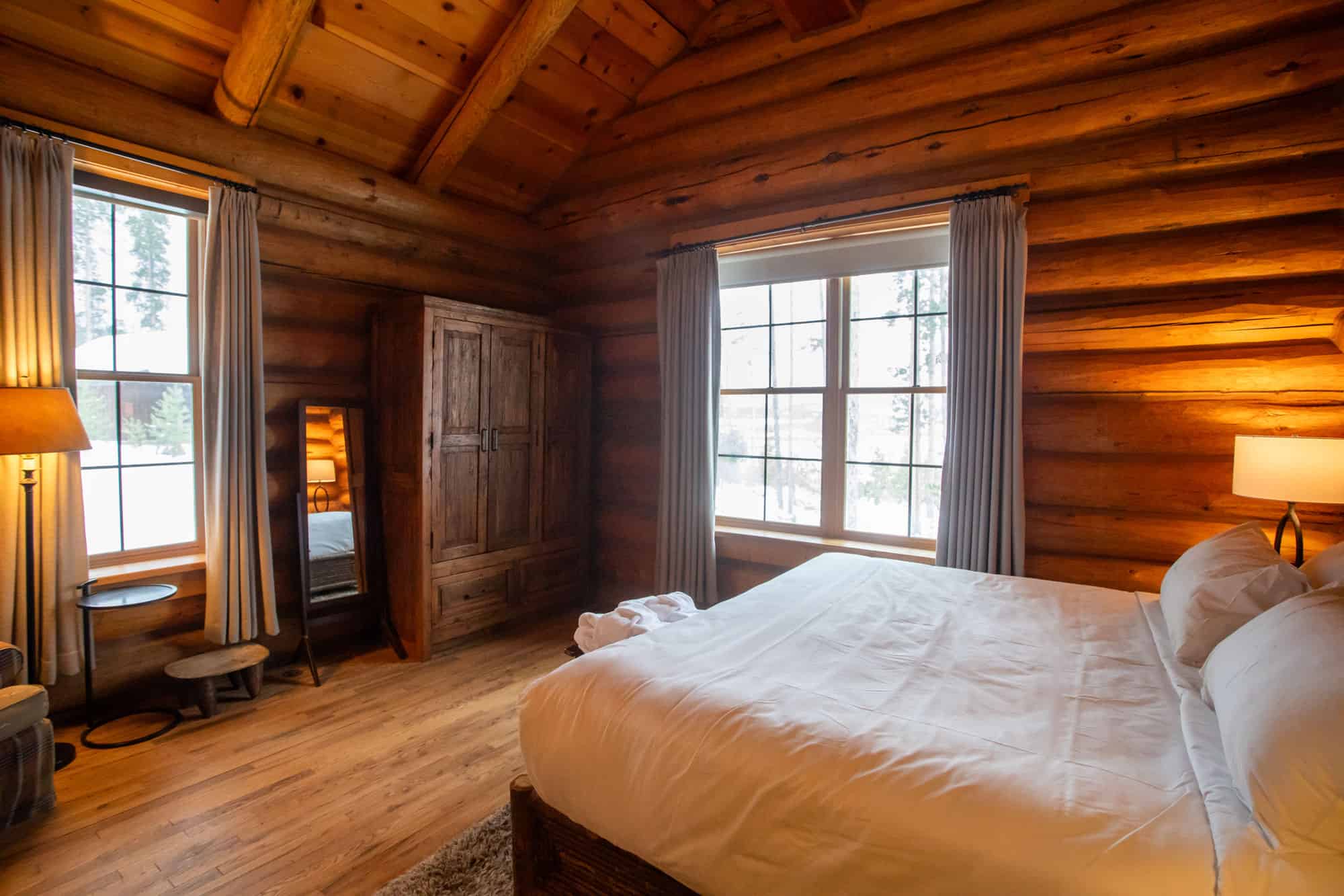 Comfortable bedroom with wooden walls and large windows at Devil's Thumb Ranch Resort & Spa.