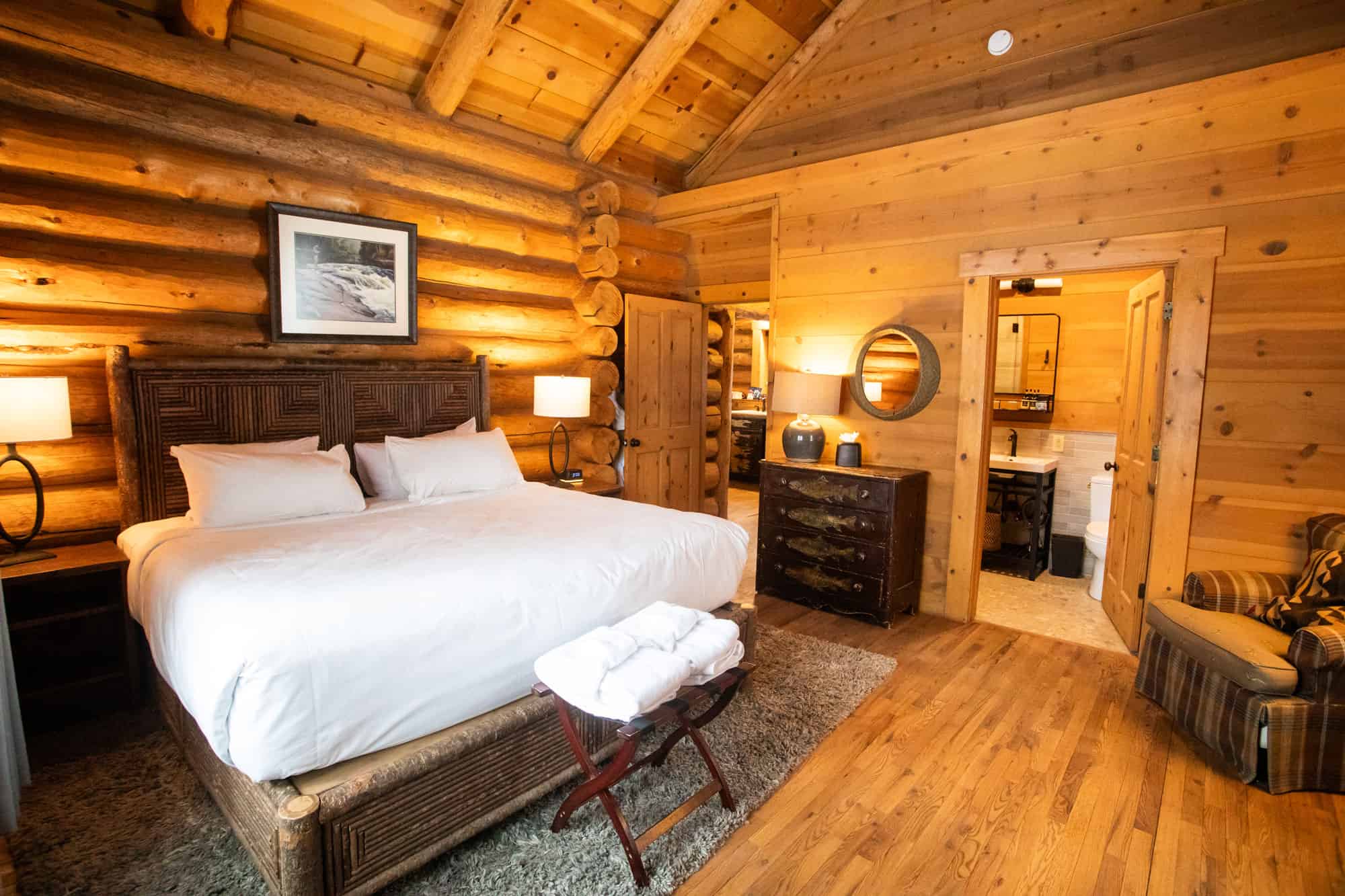A warm, inviting bedroom in a rustic log cabin with wooden walls, a large bed, and soft lighting at.