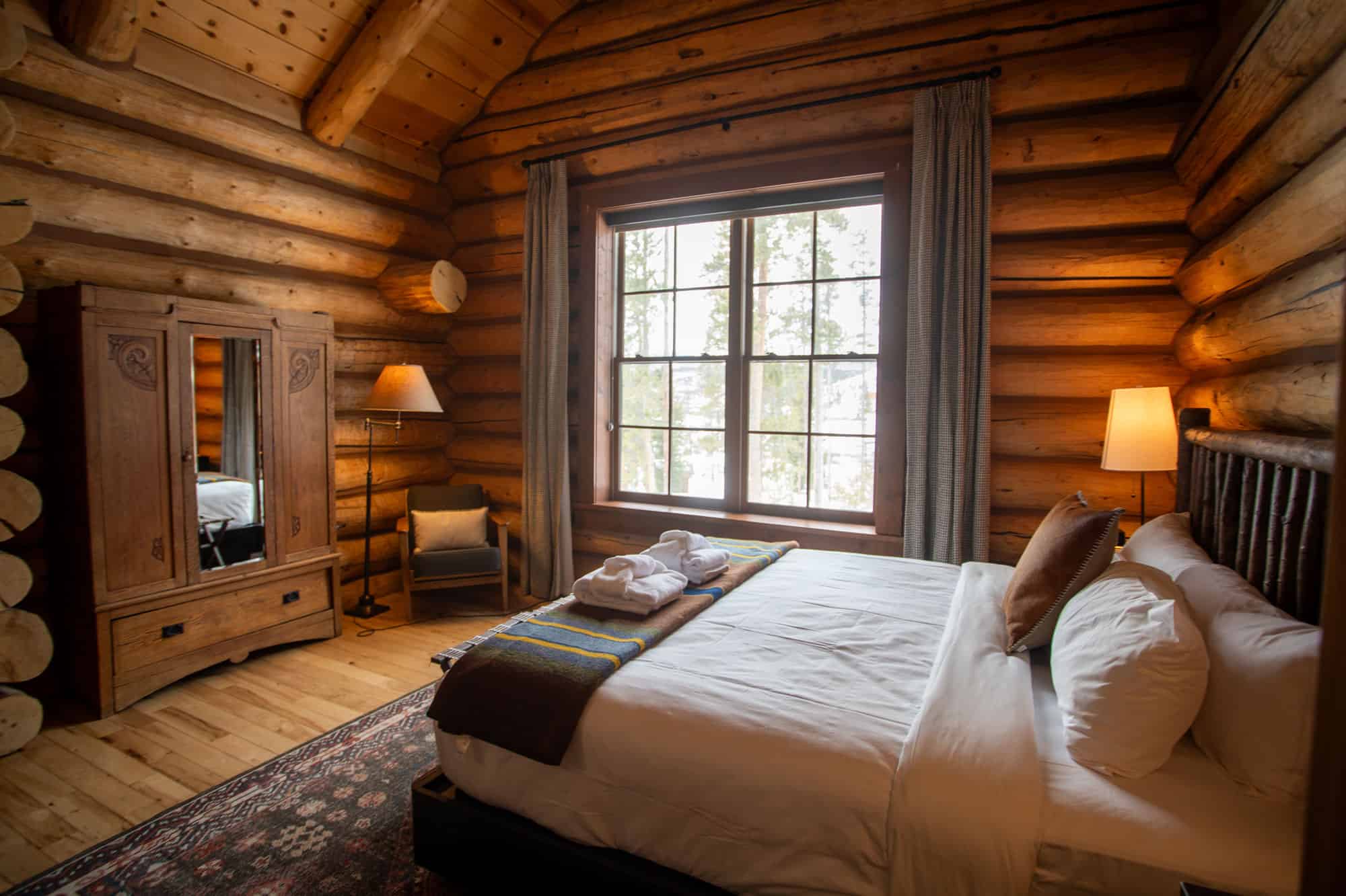 Cozy log cabin bedroom at Devil's Thumb Ranch with rustic wood walls, large window, and comfortable.