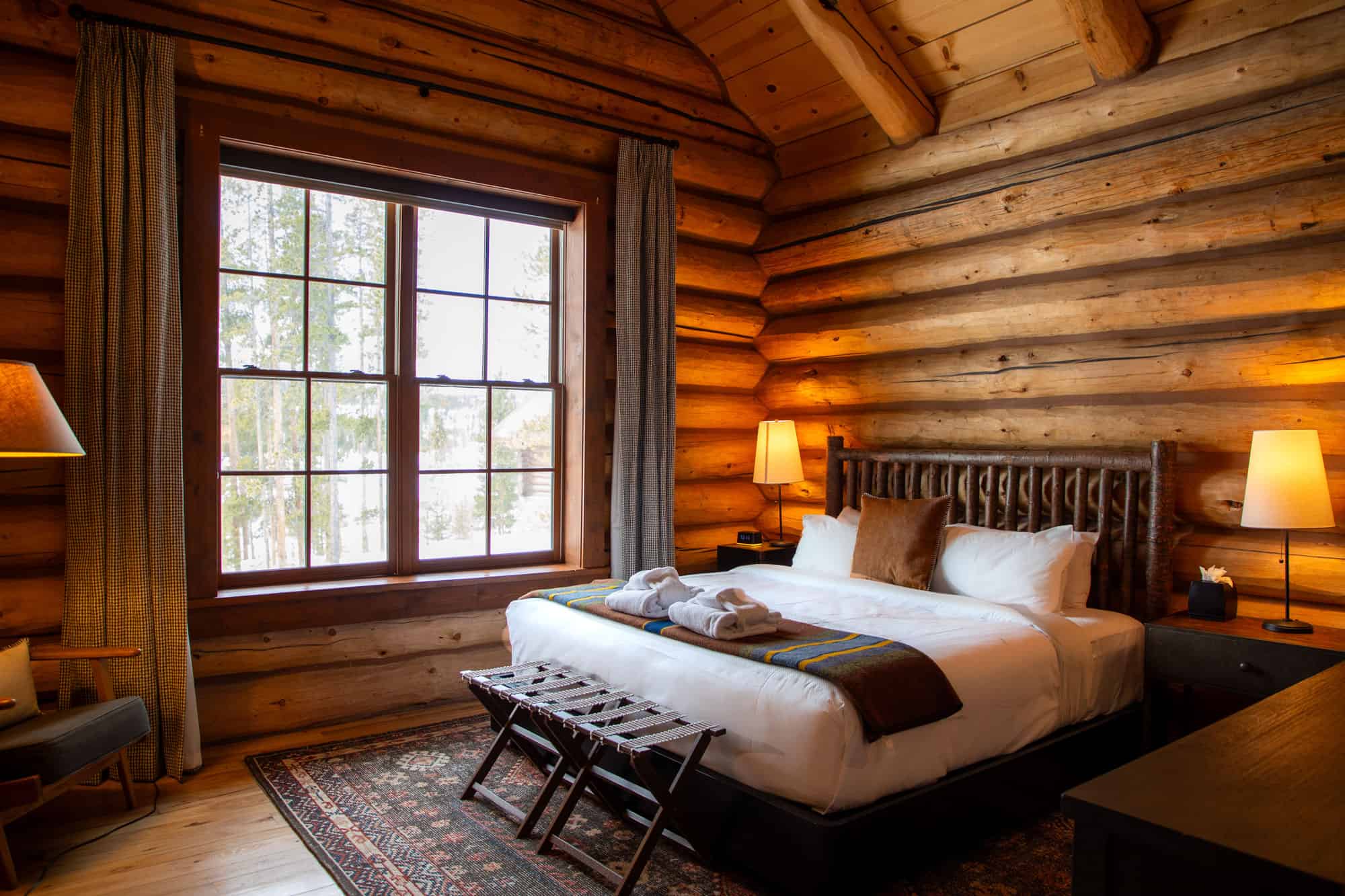 Rustic log cabin bedroom at Devil's Thumb Ranch with large window and cozy decor.