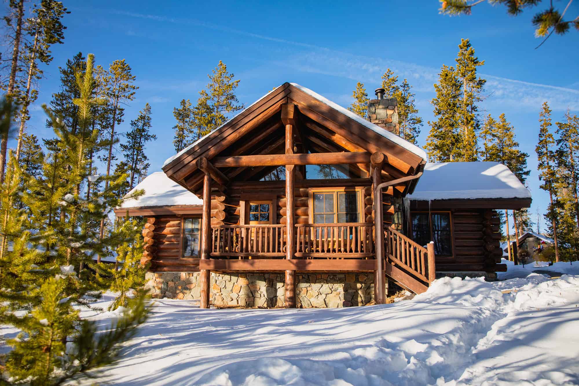 Cozy wooden cabin surrounded by snow and pine trees at Devil's Thumb Ranch Resort & Spa.