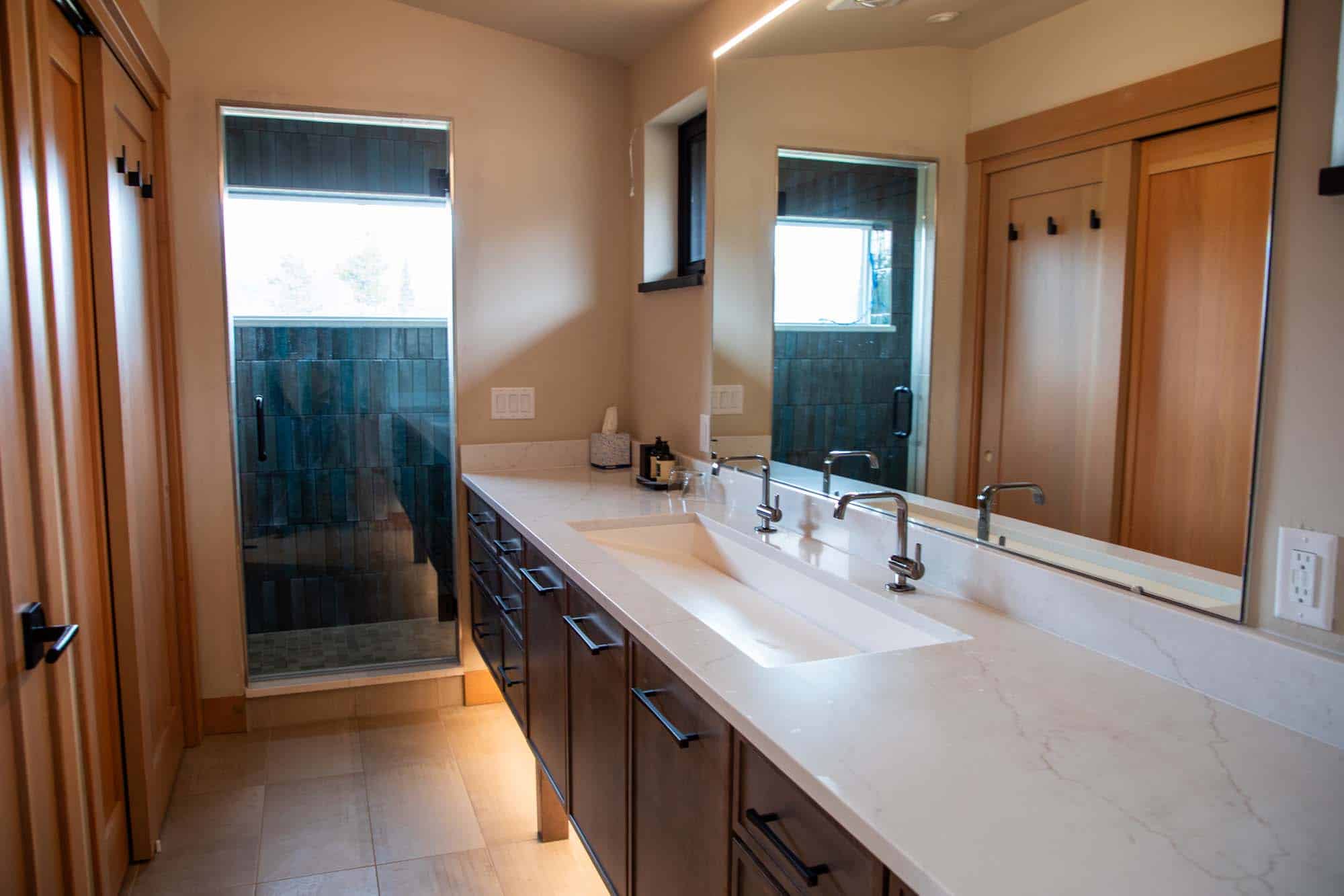 Modern bathroom with dual sinks, wooden cabinets, and a glass shower at Devil's Thumb Ranch.