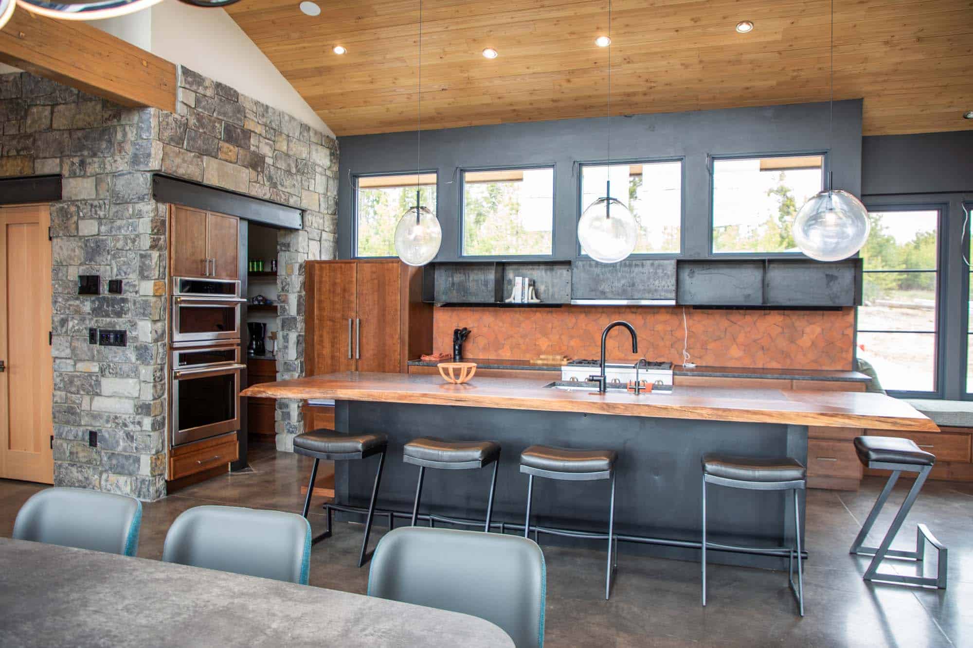 Modern kitchen featuring stone accents, wooden ceiling, and large windows at Devil's Thumb Ranch Res.