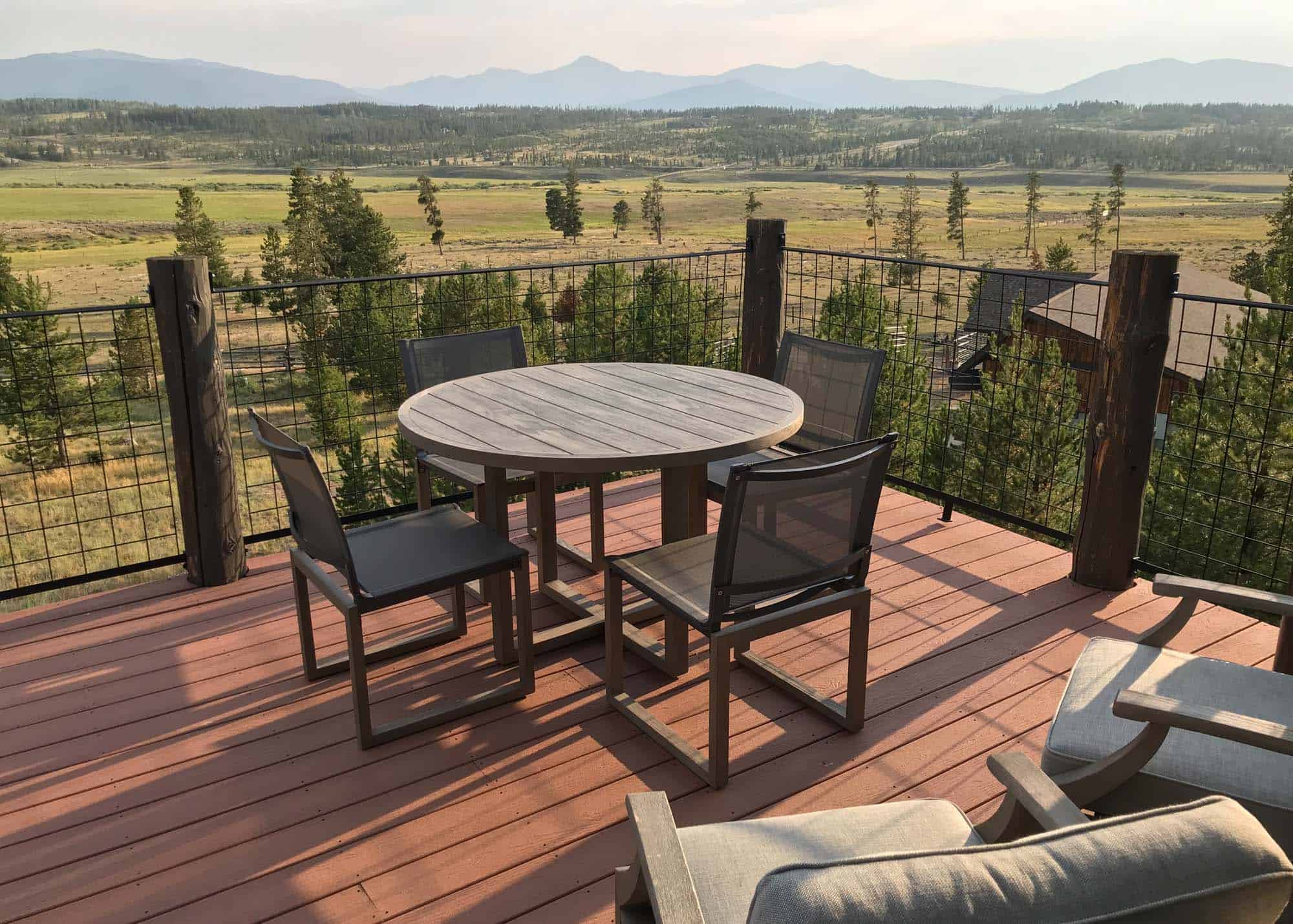 Scenic outdoor deck with table and chairs overlooking mountain landscape.