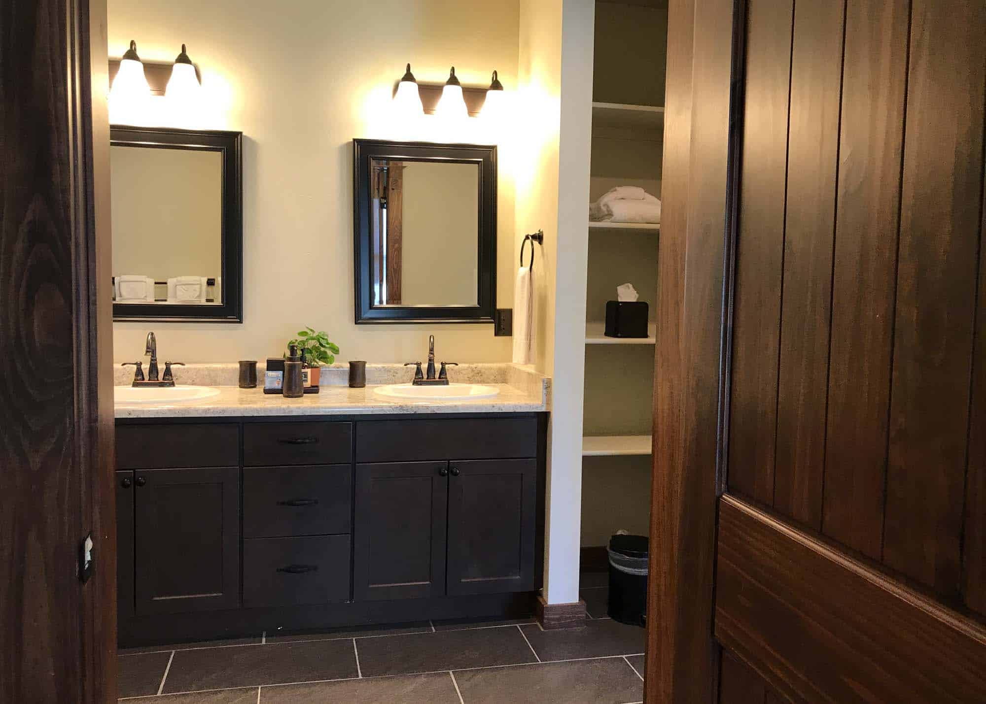 Modern bathroom with dual sinks, mirrors, and wooden accents at Devil's Thumb Ranch.