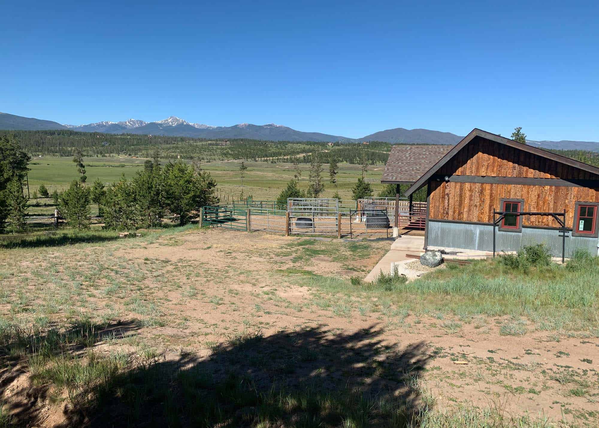 Scenic view of farm with mountains in the background at Devil's Thumb Ranch Resort & Spa.