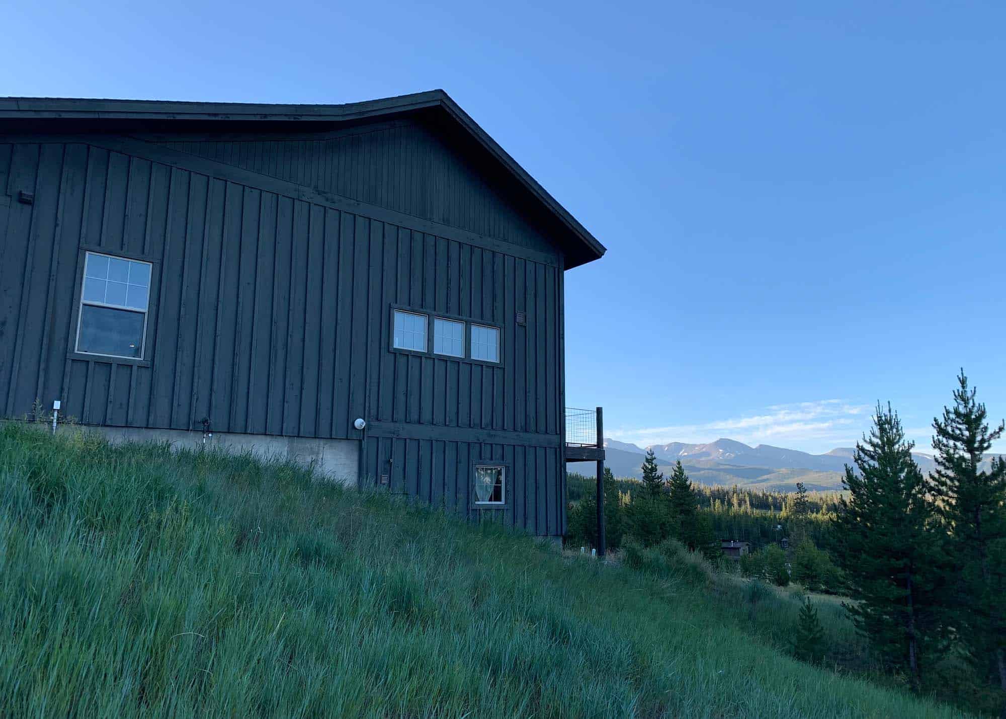 Exterior view of the dark blue building at Devil's Thumb Ranch Resort & Spa with scenic mountain and.