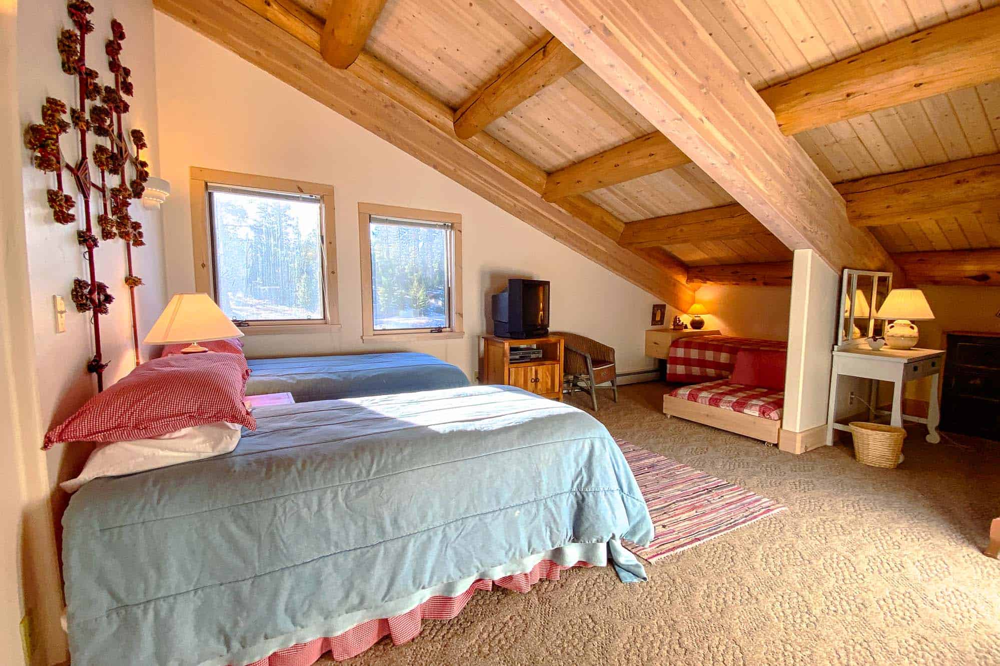 Cozy bedroom with rustic wooden beams and large windows at Devil's Thumb Ranch.
