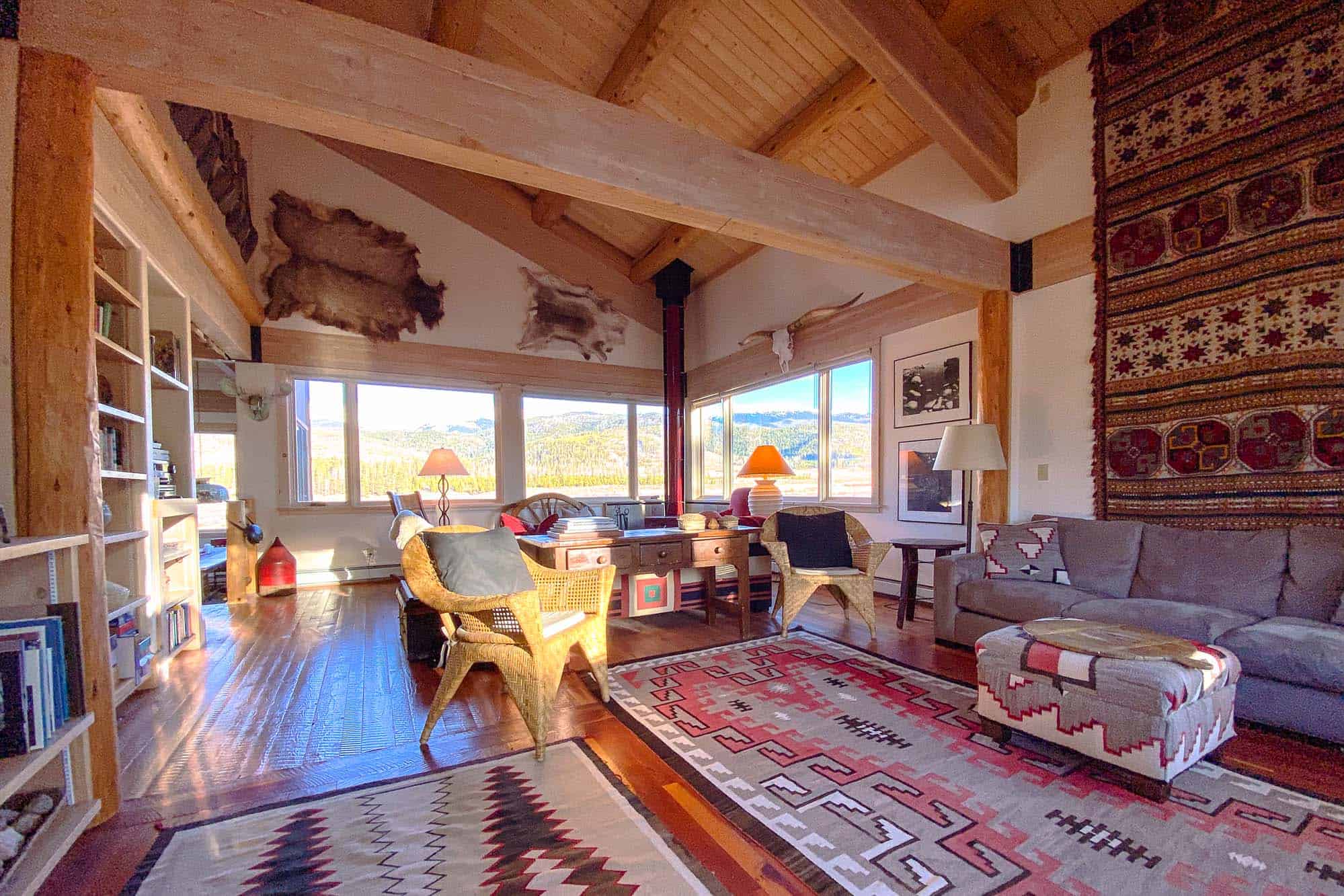 Interior view of a cozy lounge at Devil's Thumb Ranch Resort & Spa with wooden beams, colorful rugs,.