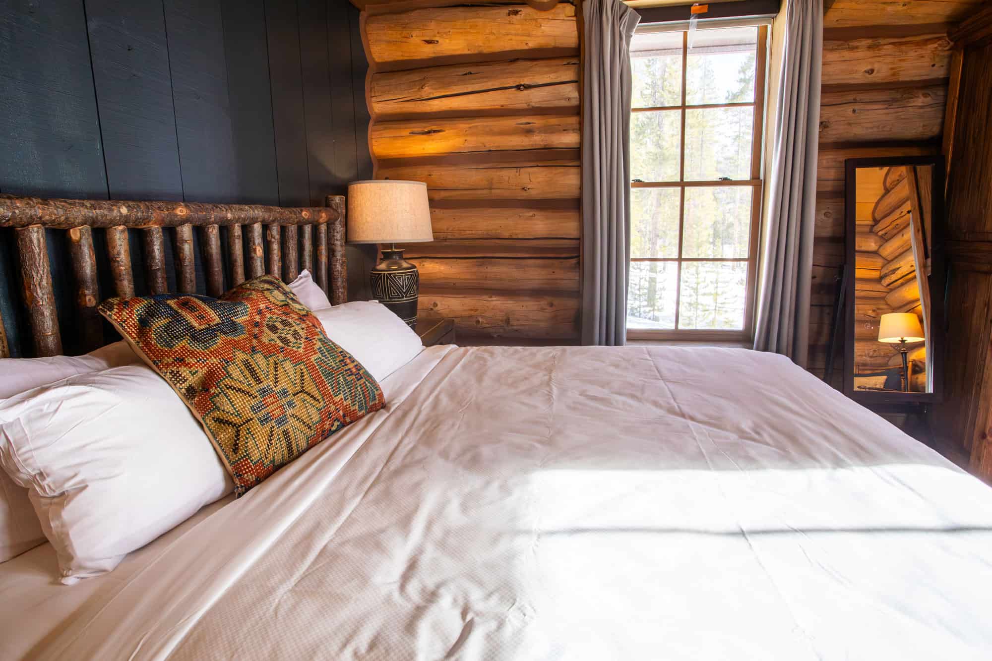 Cozy bedroom at Devil's Thumb Ranch with rustic wood walls, a large bed, and natural light from a wi.