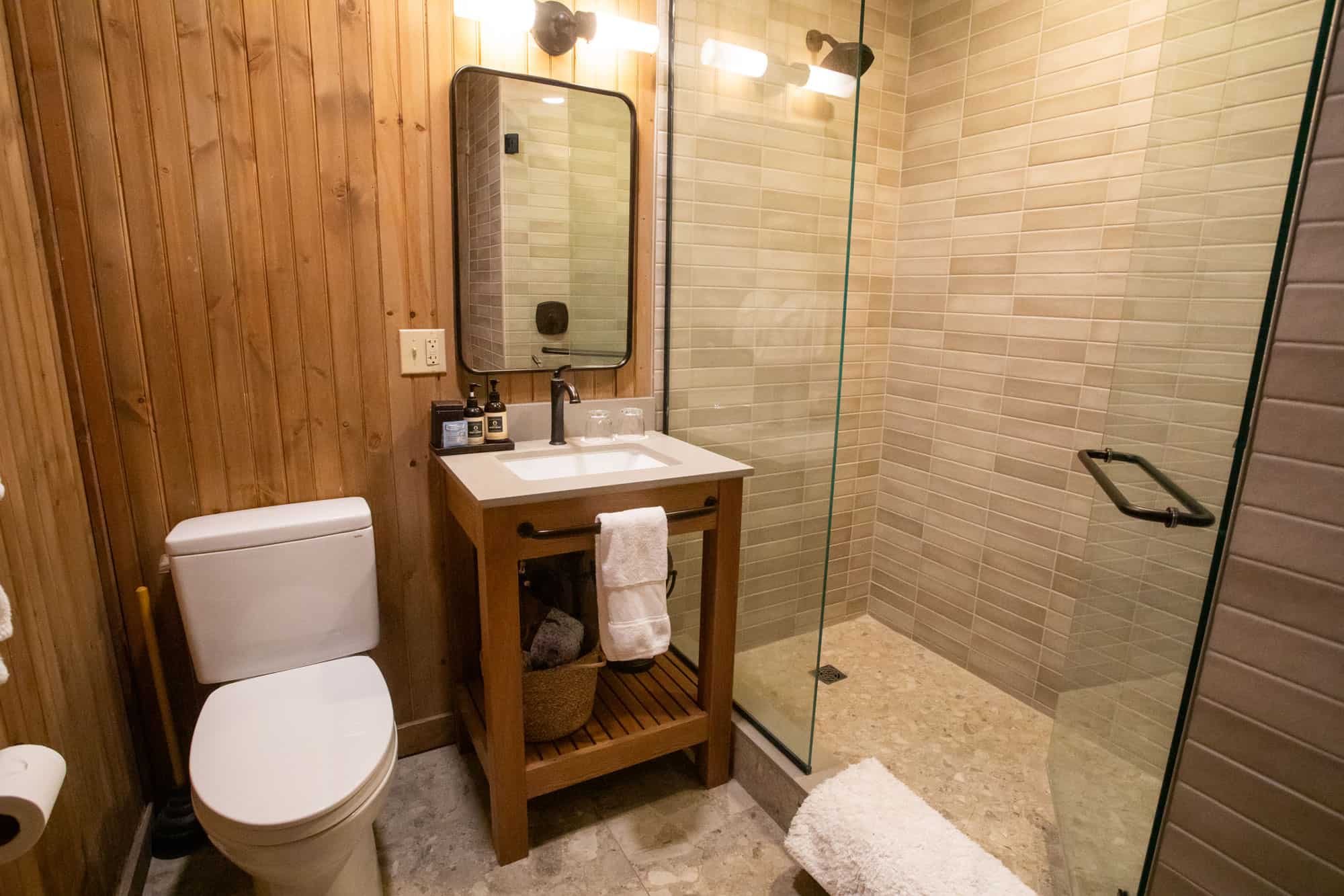 Bathroom with wooden wall paneling, modern sink, and glass-enclosed shower.