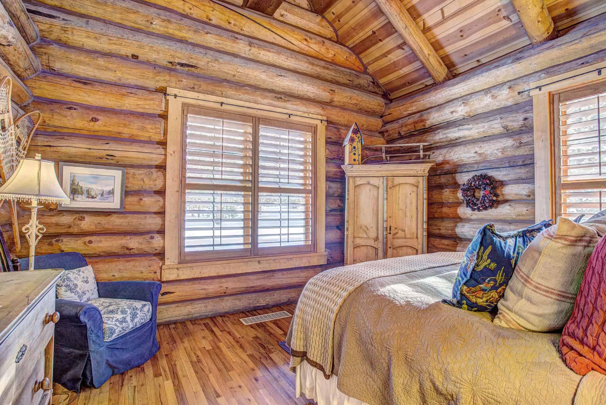 Cozy log cabin bedroom with wooden walls, large windows, and rustic decor at Devil's Thumb Ranch Res.