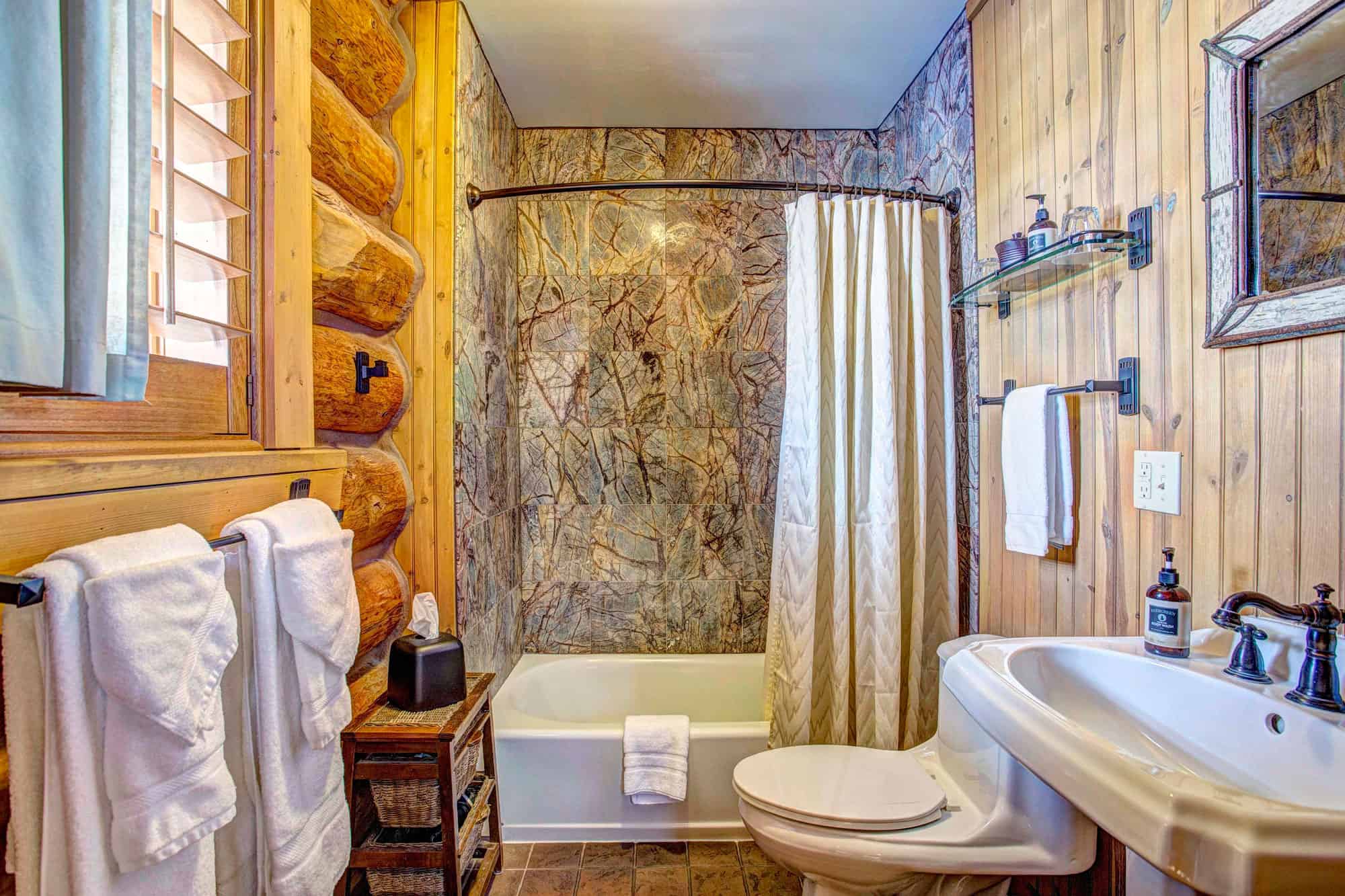 Rustic bathroom with log walls, bathtub, and vintage decor at Devil's Thumb Ranch Resort & Spa.