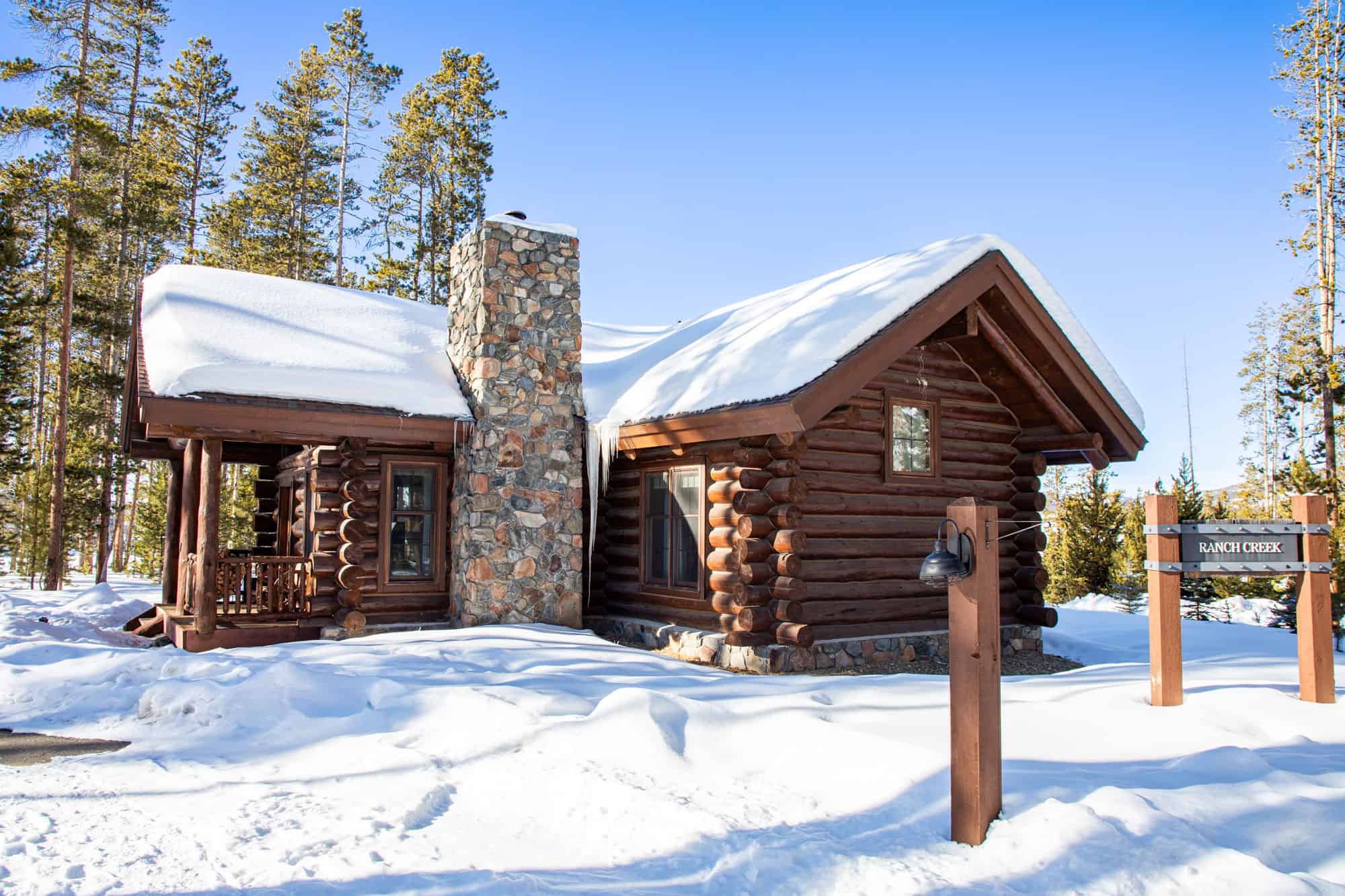 Rustic log cabin with stone chimney in snowy landscape at Devil's Thumb Ranch Resort & Spa.