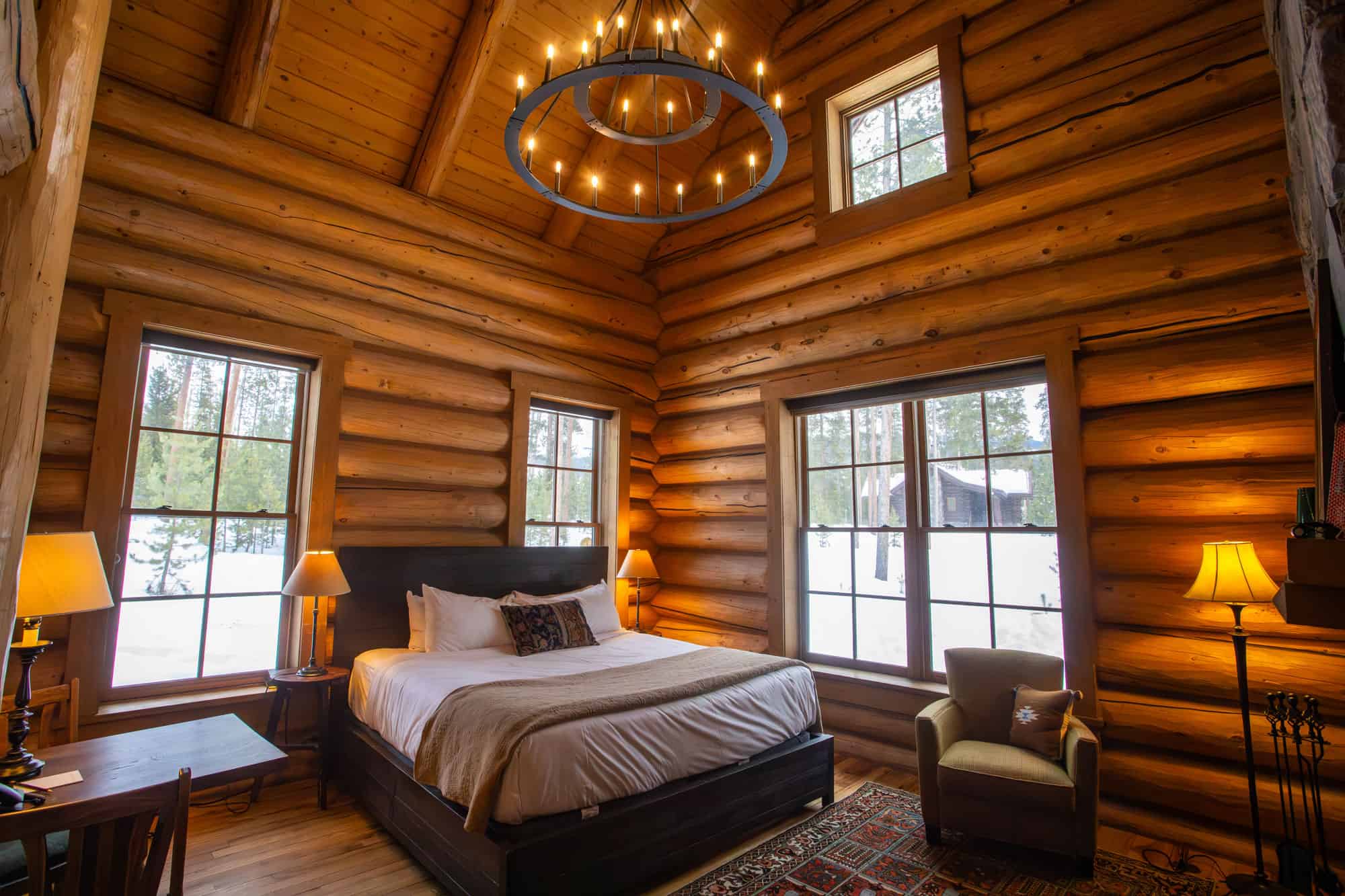 Cozy log cabin bedroom with large windows and rustic decor at Devil's Thumb Ranch.