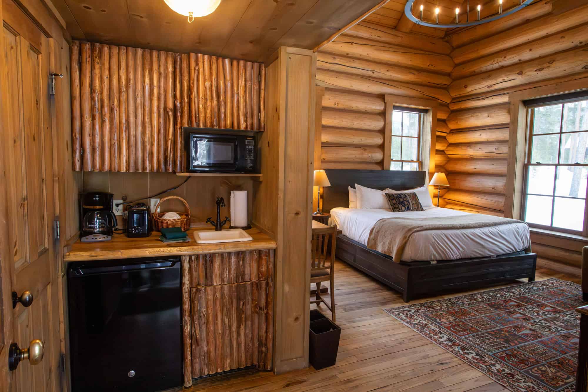 Cozy rustic bedroom with wooden walls and large windows at Devil's Thumb Ranch.