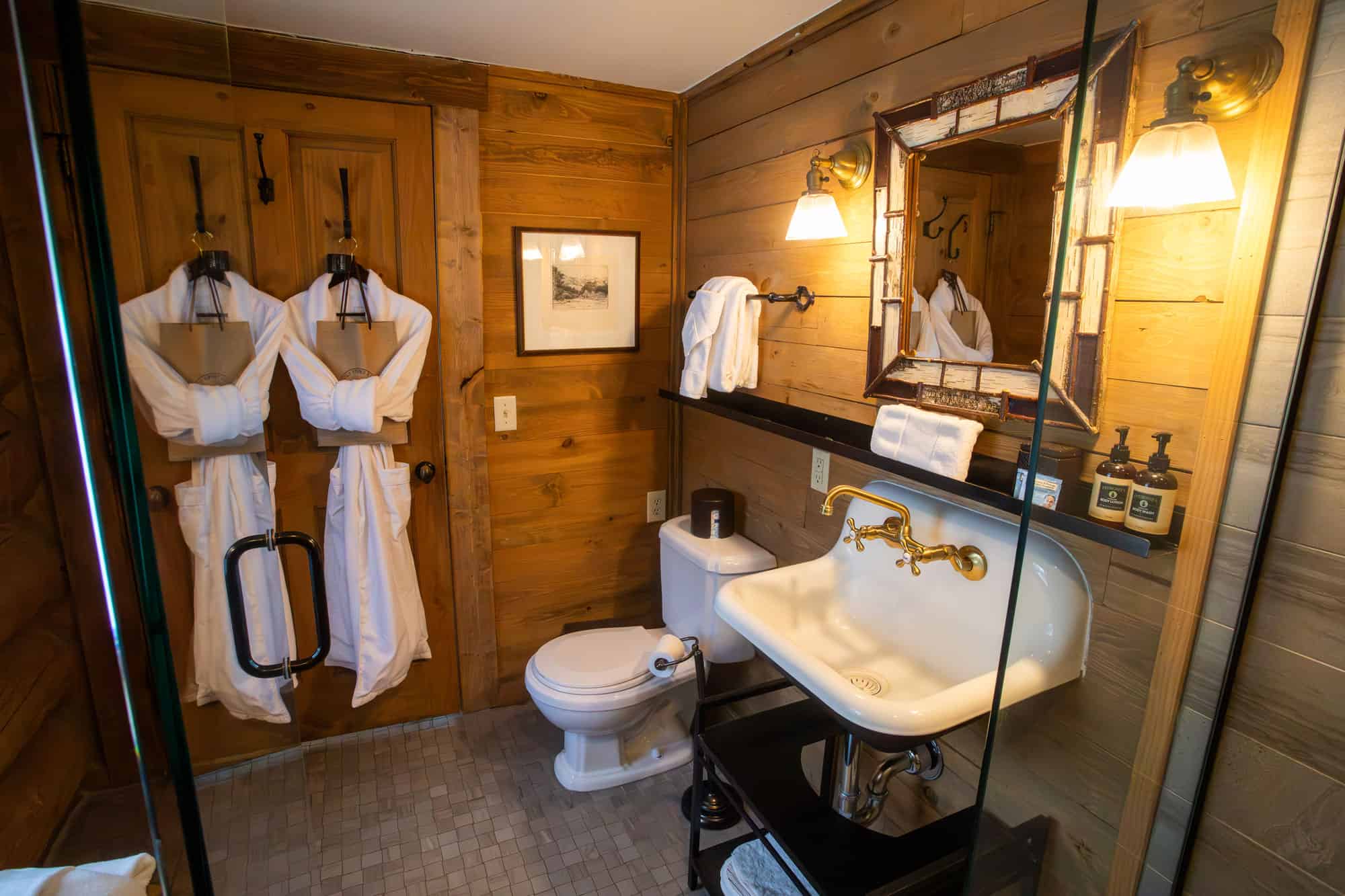 Cozy rustic bathroom with wooden walls, vintage sink, and warm lighting at Devil's Thumb Ranch.