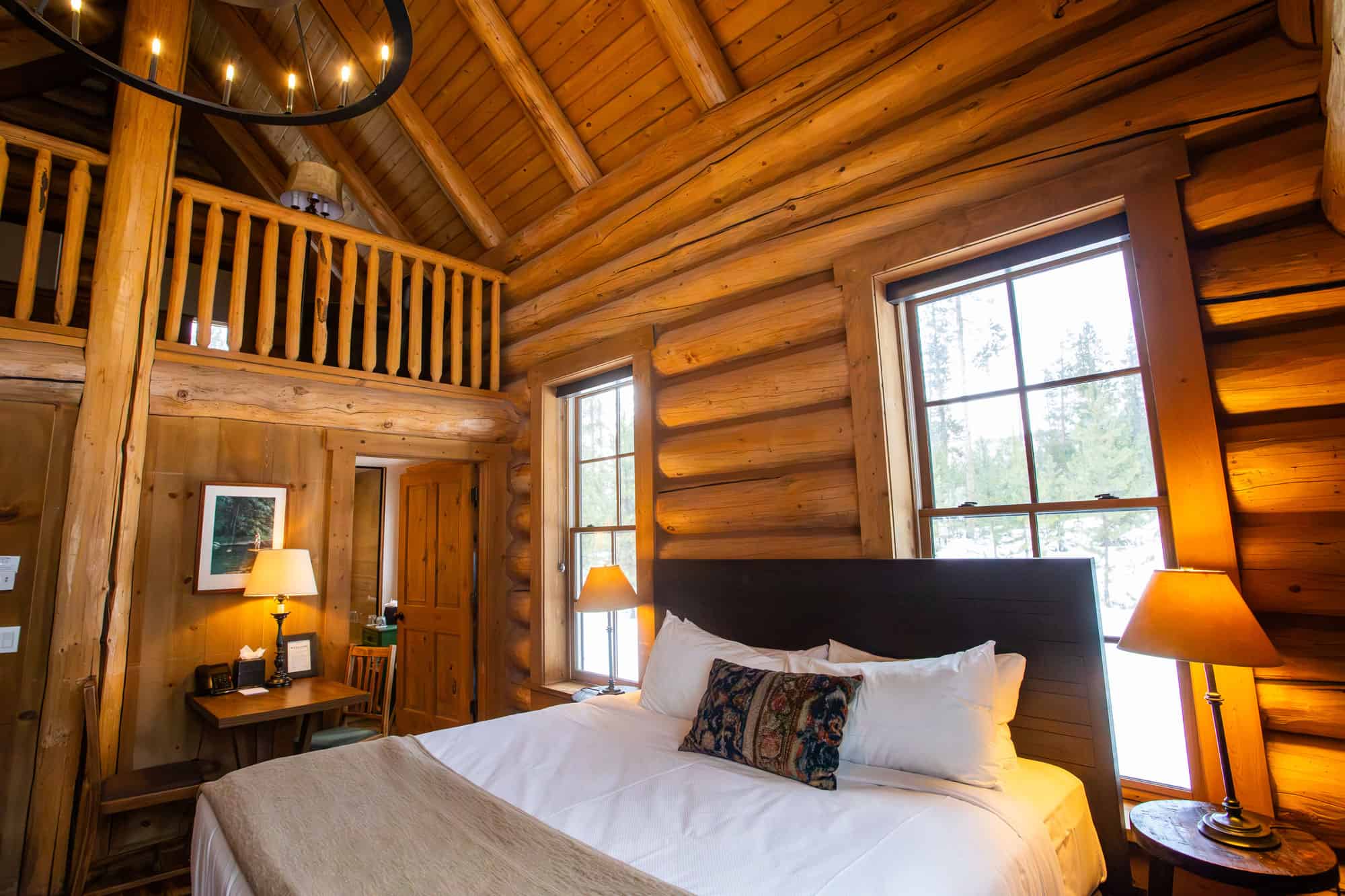 Rustic bedroom with wooden walls, large windows, and cozy decor at Devil's Thumb Ranch.