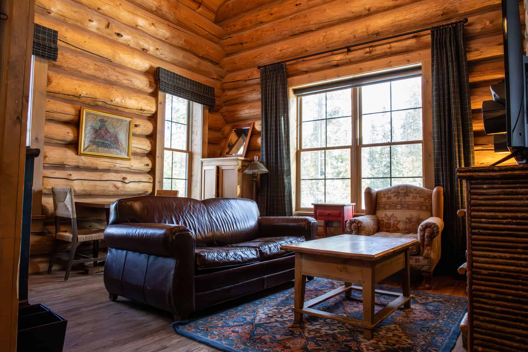 Cozy log cabin living room with leather sofa, armchair, and rustic decor at Devil's Thumb Ranch.