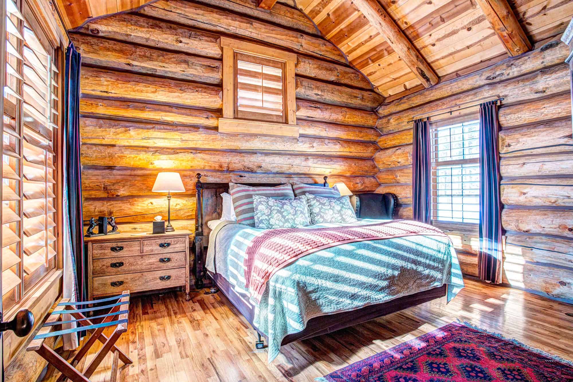 Rustic log cabin bedroom at Devil's Thumb Ranch with wooden walls and cozy bedding.