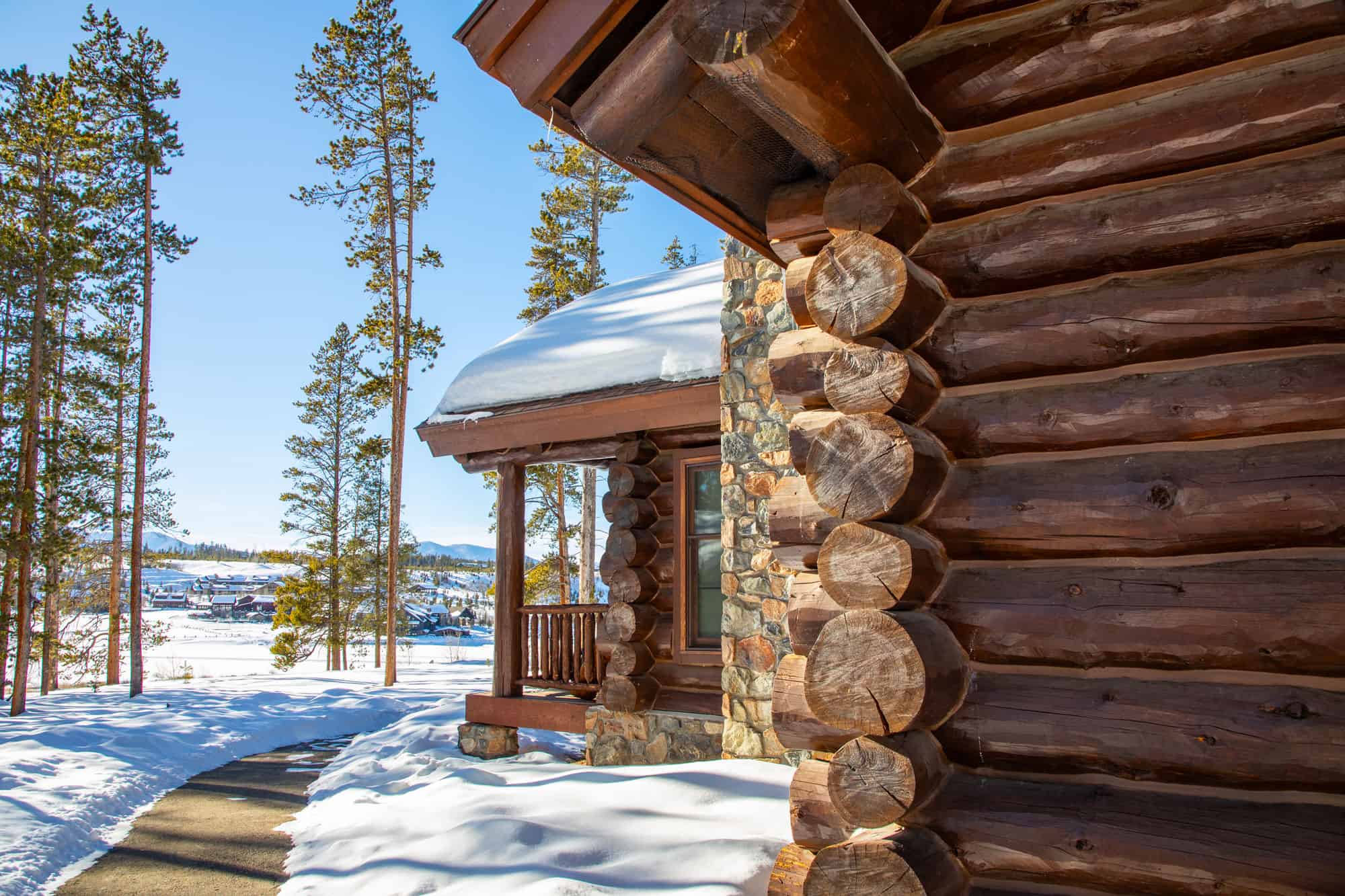 Cozy winter cabin at Devil's Thumb Ranch with snow-covered surroundings and tall pine trees.