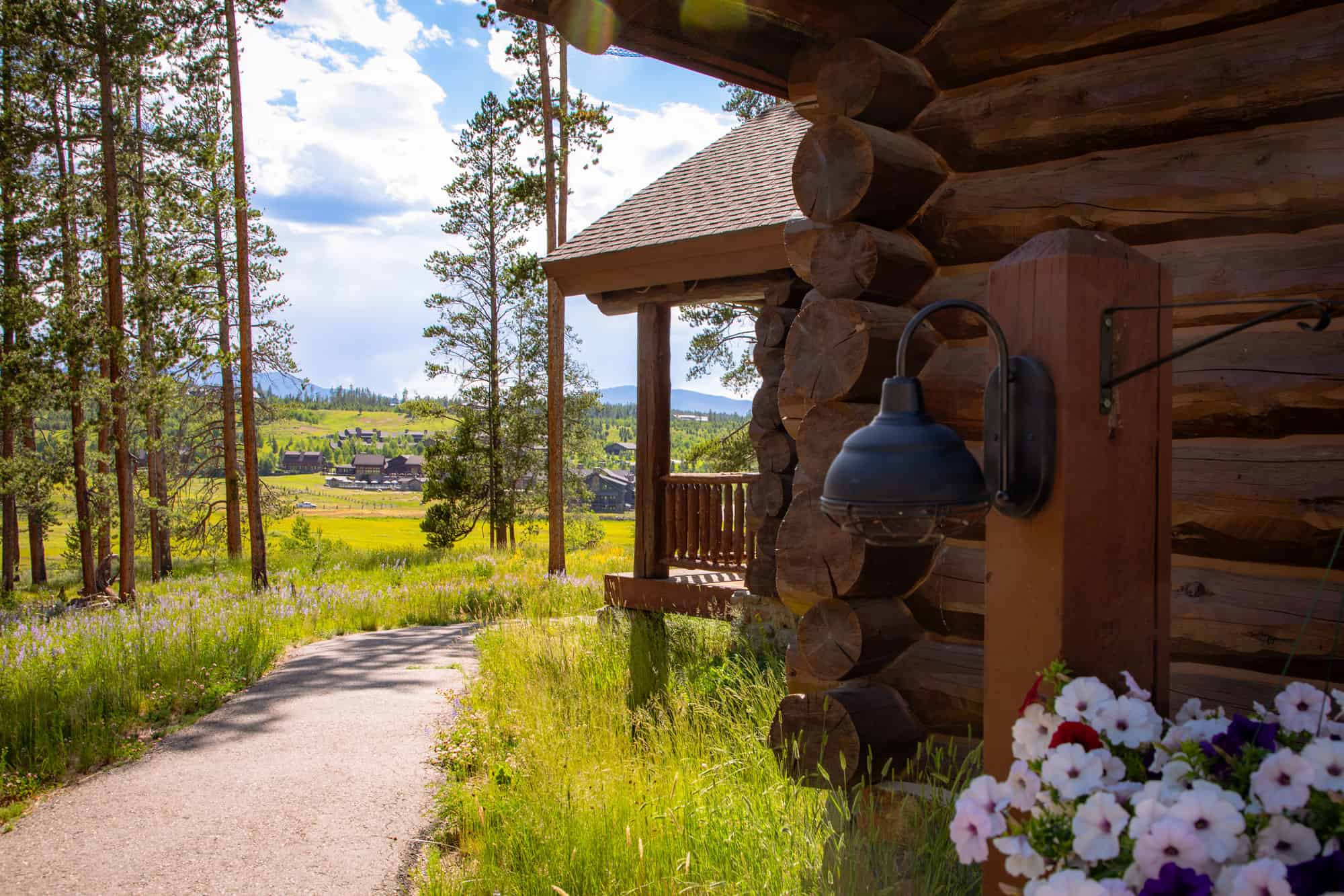 Scenic view of Devil's Thumb Ranch with a rustic log cabin and lush green landscape.