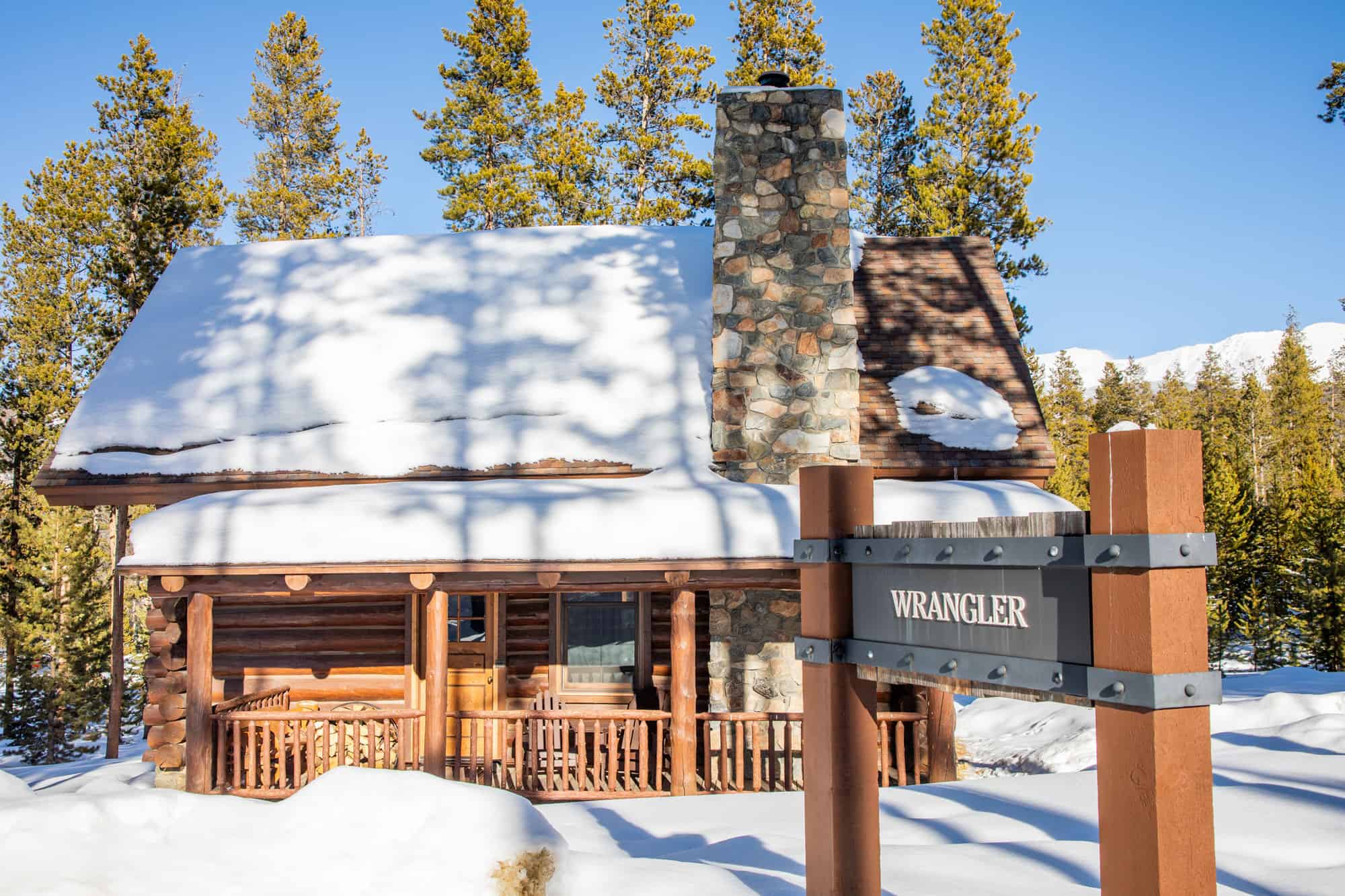 Cozy mountain cabin at Devil's Thumb Ranch with snow-covered roof and surrounding trees.