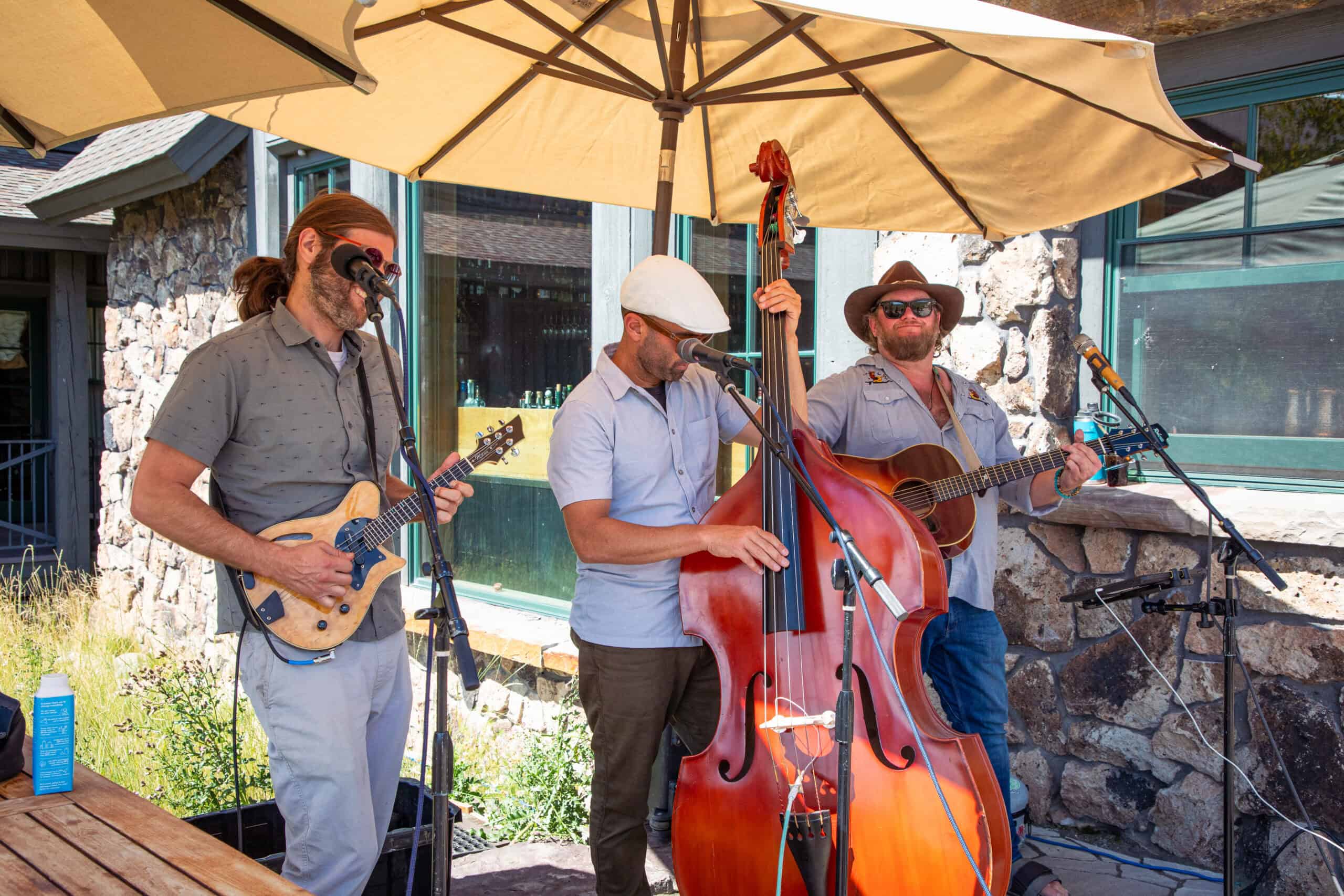 Live band performing outdoors at Devil's Thumb Ranch Resort & Spa under a large umbrella.