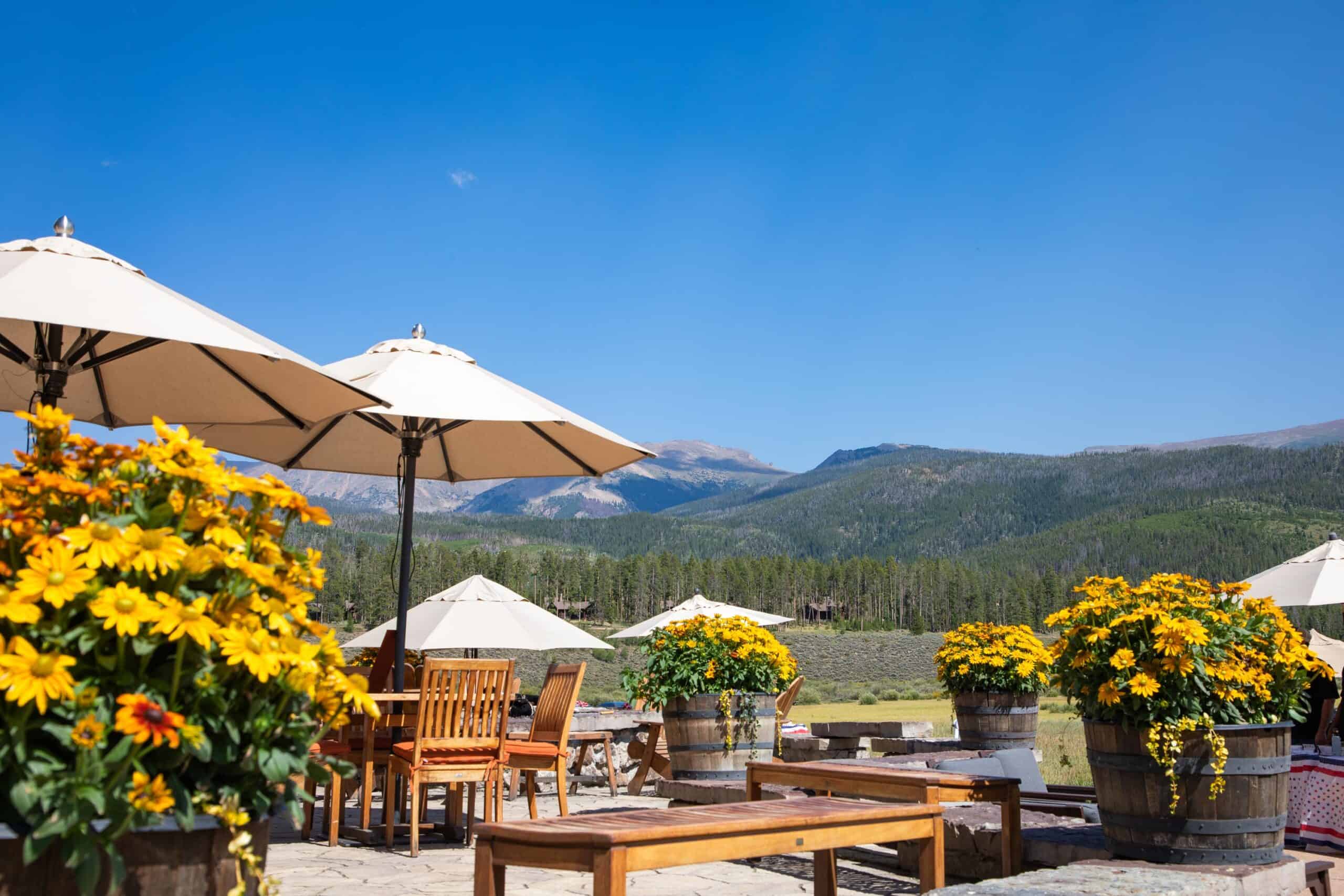 Scenic outdoor patio at Devil's Thumb Ranch with yellow flowers and mountain views.