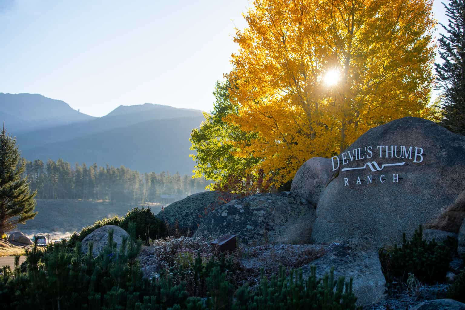 Scenic view of Devil's Thumb Ranch with autumn foliage and mountains in the background.