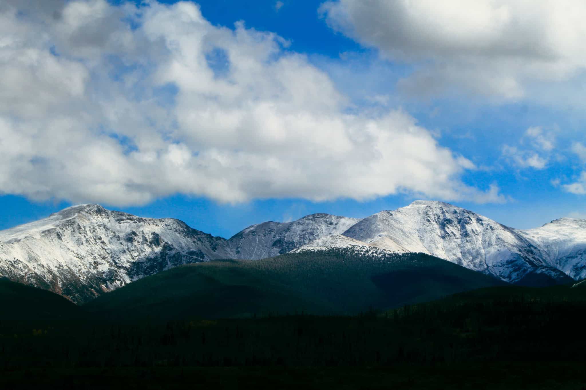 Snow-capped mountains of Devil's Thumb range under a partly cloudy sky.