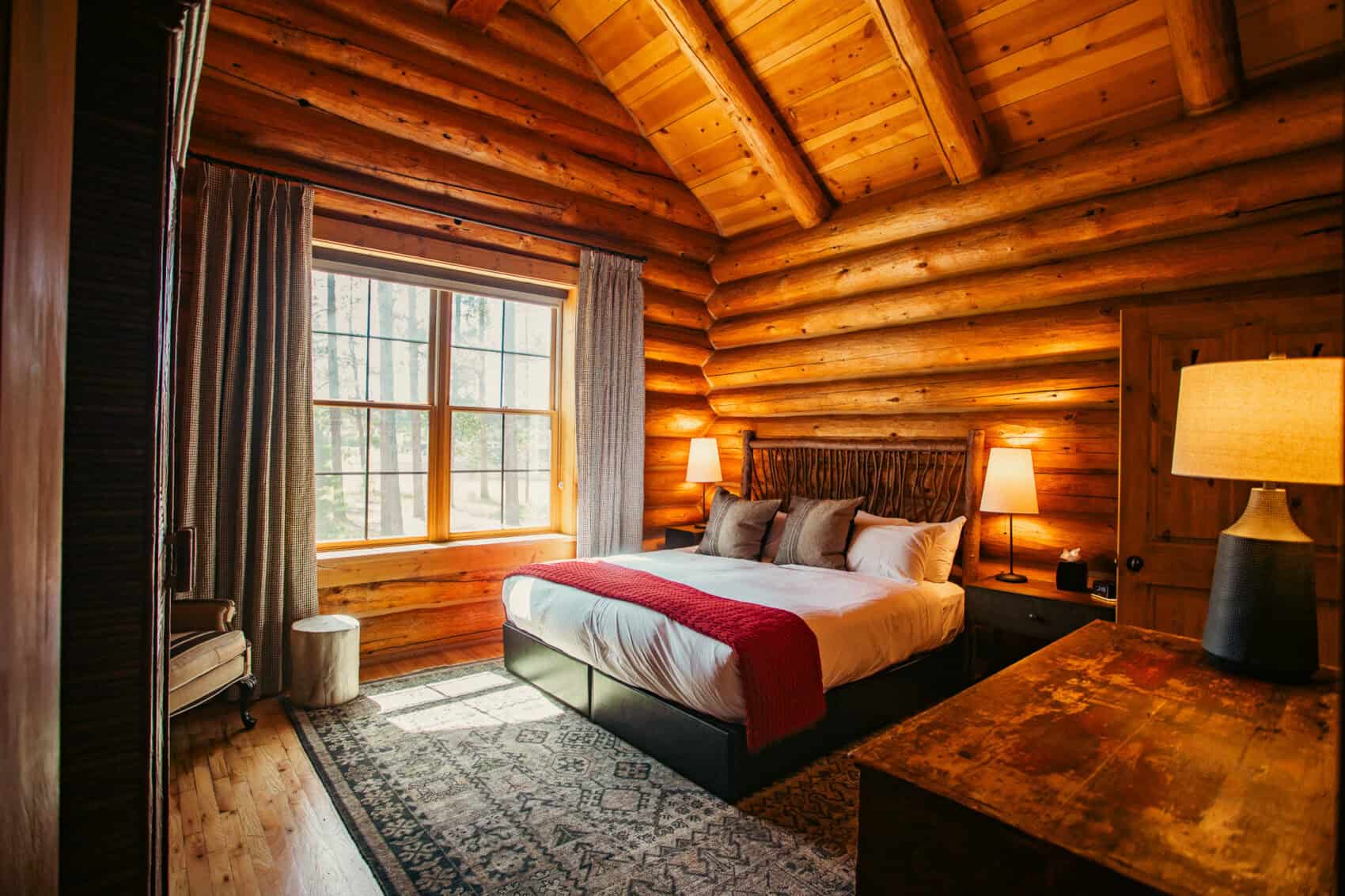 Interior view of a rustic log cabin bedroom at Devil's Thumb Ranch Resort & Spa with wooden walls an.