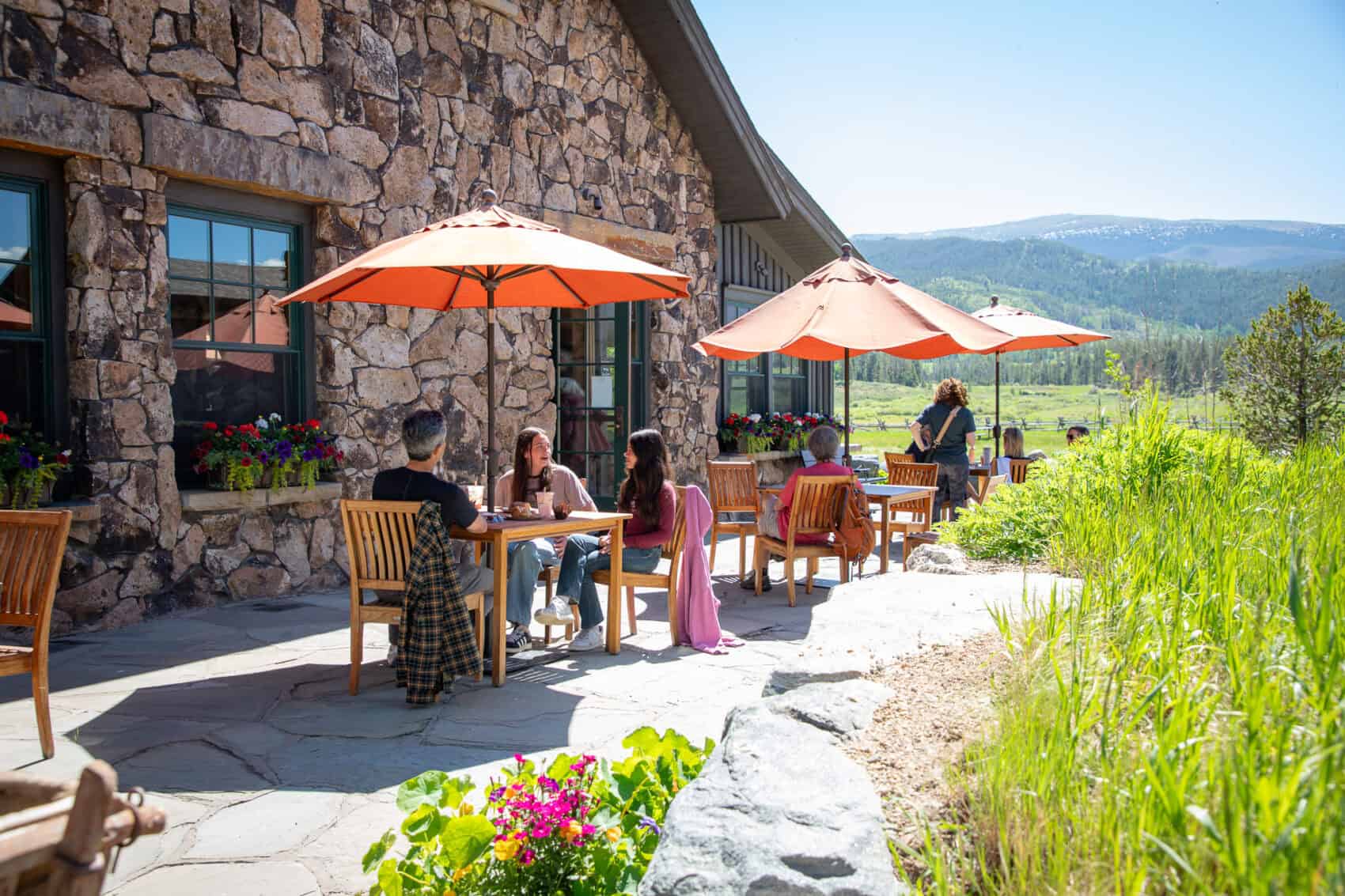 Outdoor dining area at Devil's Thumb Ranch with guests enjoying meals under umbrellas.