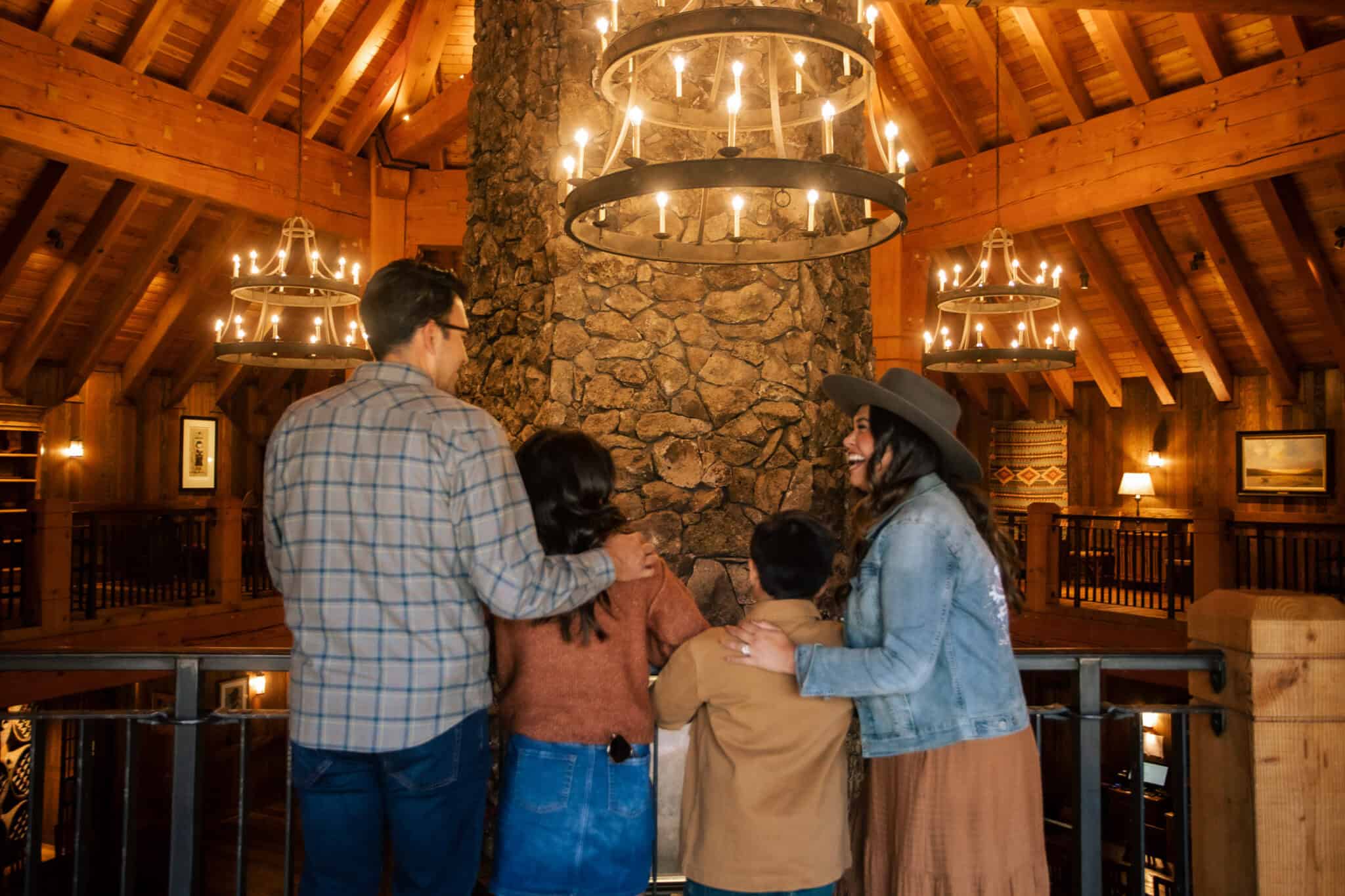 Group of four people enjoying conversation in a rustic lodge setting with wooden beams and chandelie.