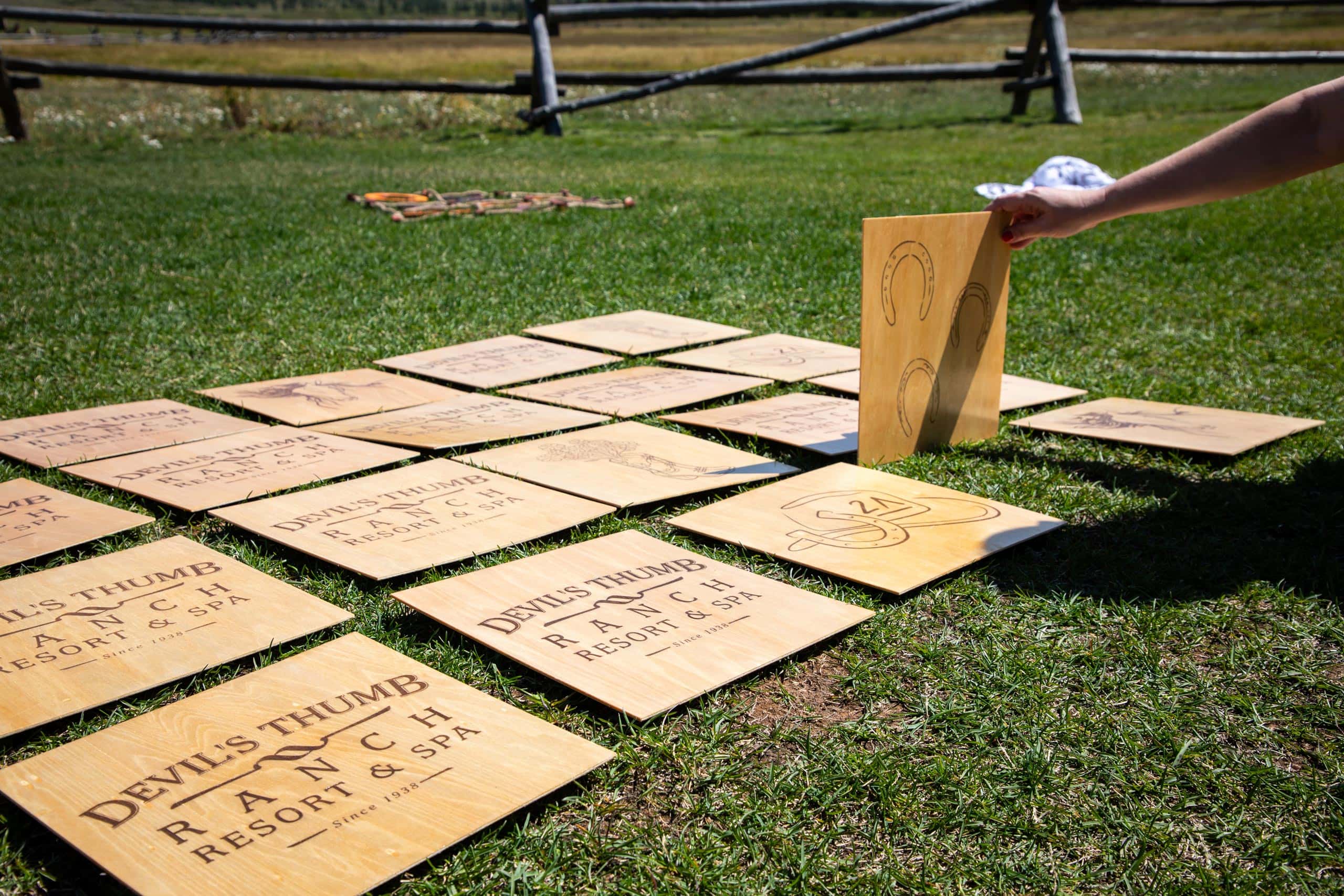 Wooden signs for Devil's Thumb Ranch Resort & Spa on grass.