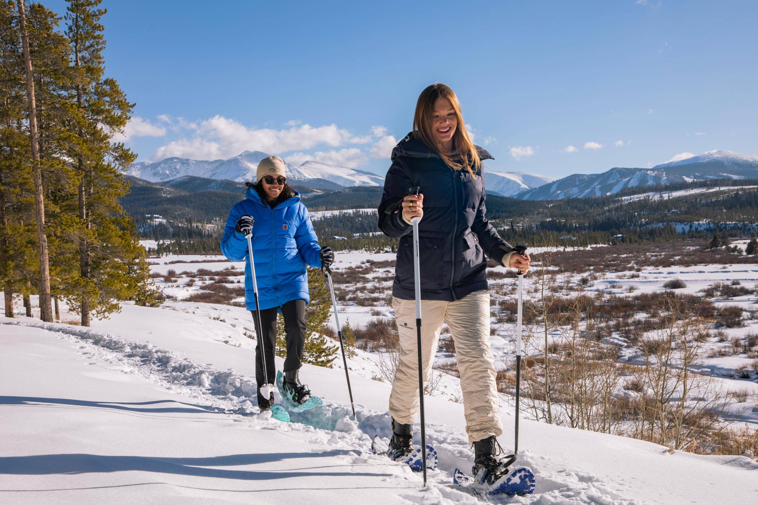 Two women snowshoeing in snowy mountain landscape at Devil's Thumb Ranch.