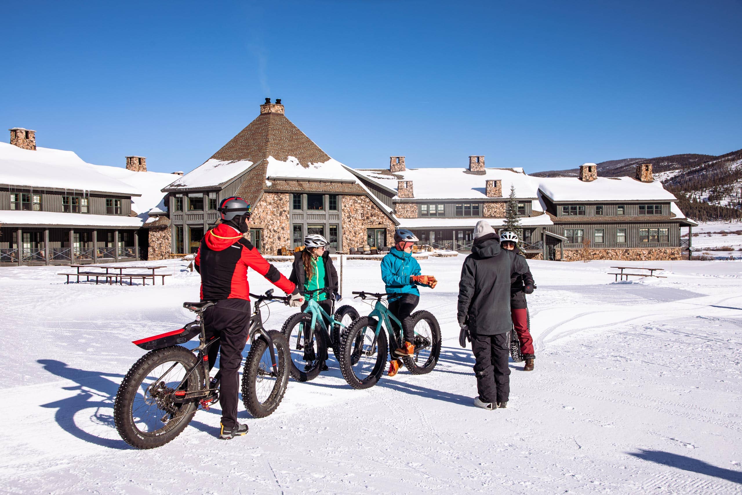Group of people with fat bikes in front of Devil's Thumb Ranch in winter.