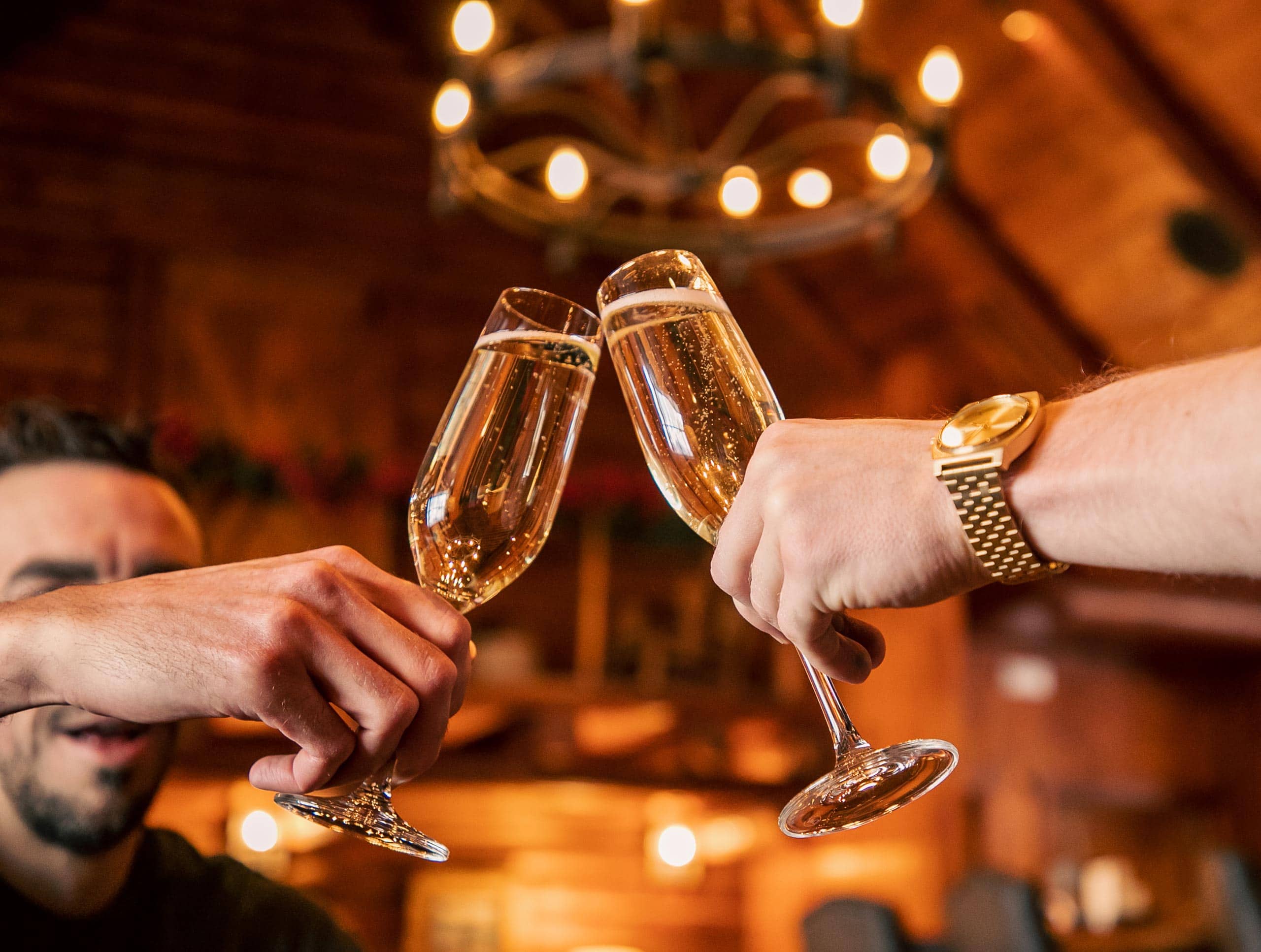 People clinking champagne glasses in a cozy rustic setting.