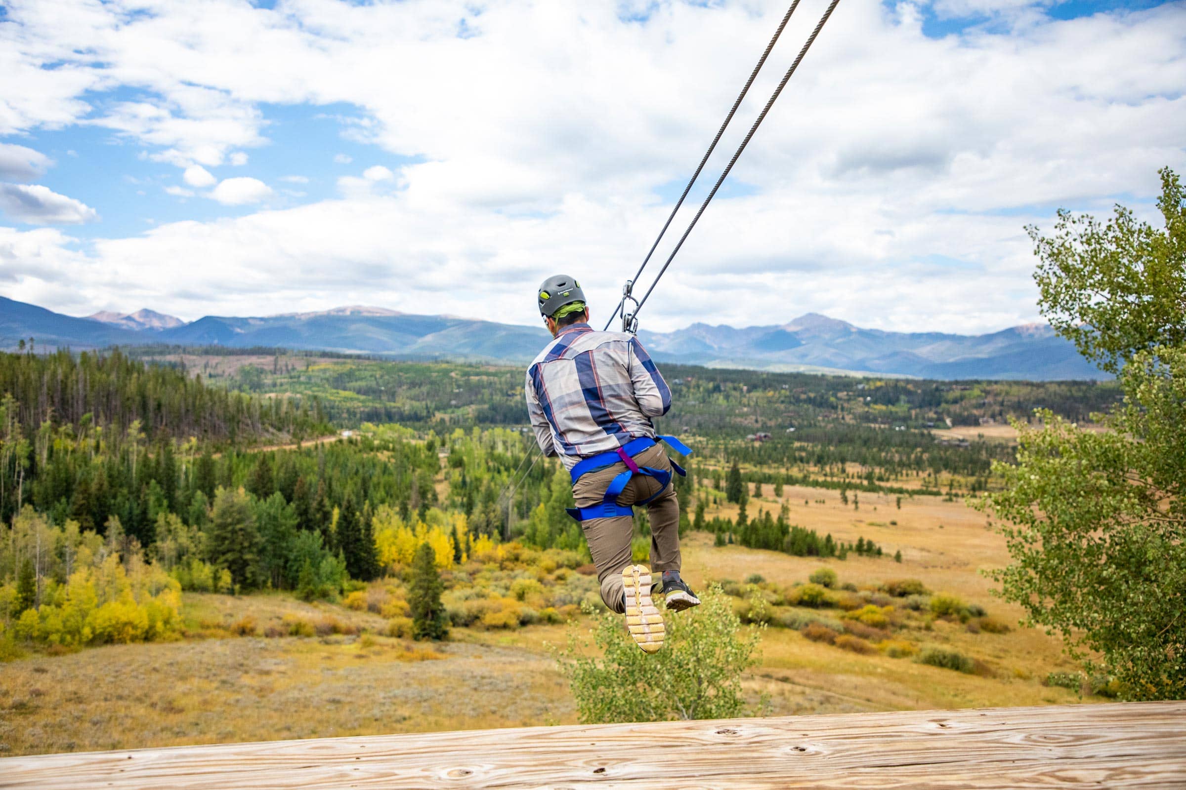 Person enjoying zip lining over scenic mountain landscape at Devil's Thumb Ranch.