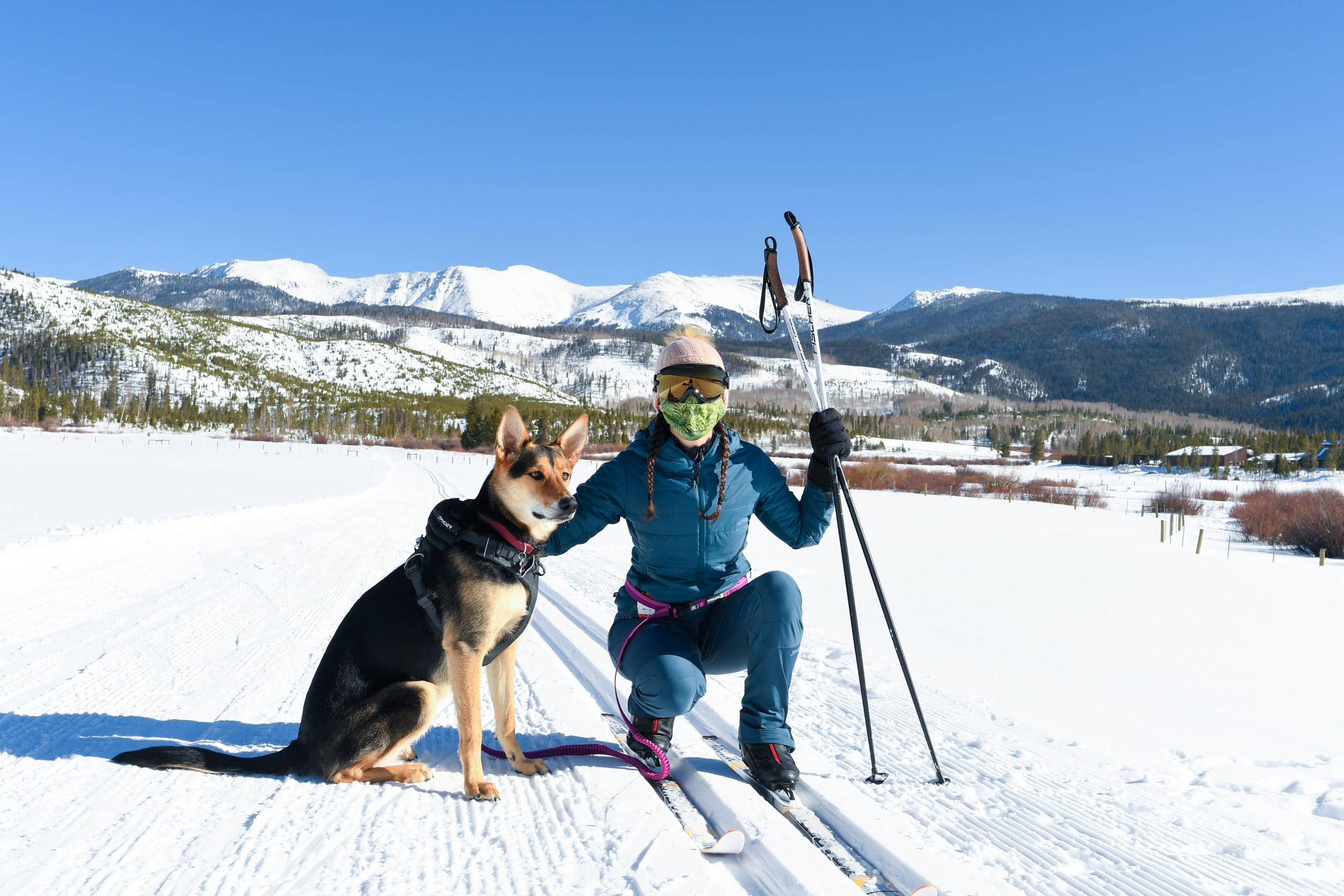 Person skiing with dog in snowy mountain landscape at Devil's Thumb Ranch.