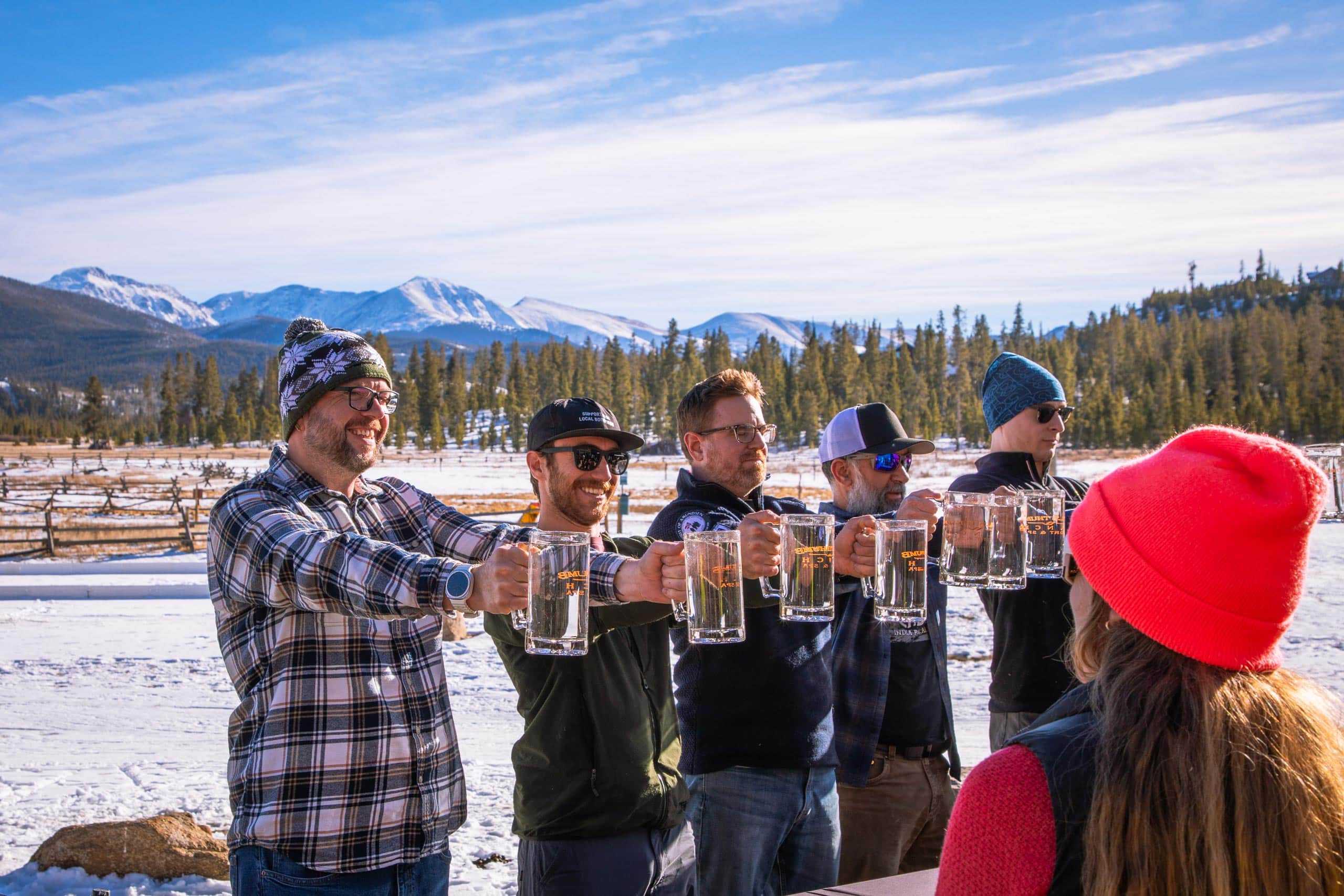 Group of friends enjoying drinks outdoors at Devil's Thumb Ranch in winter.