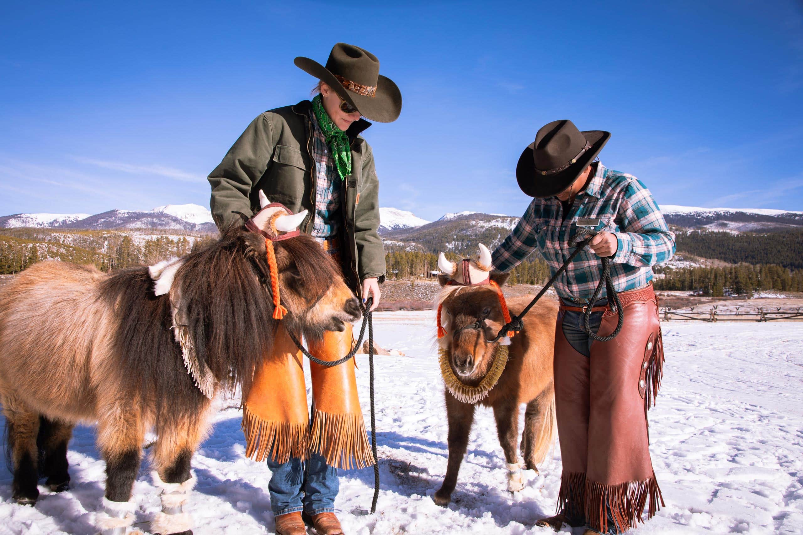 Two cowboys with ponies in snowy landscape at Devil's Thumb Ranch.