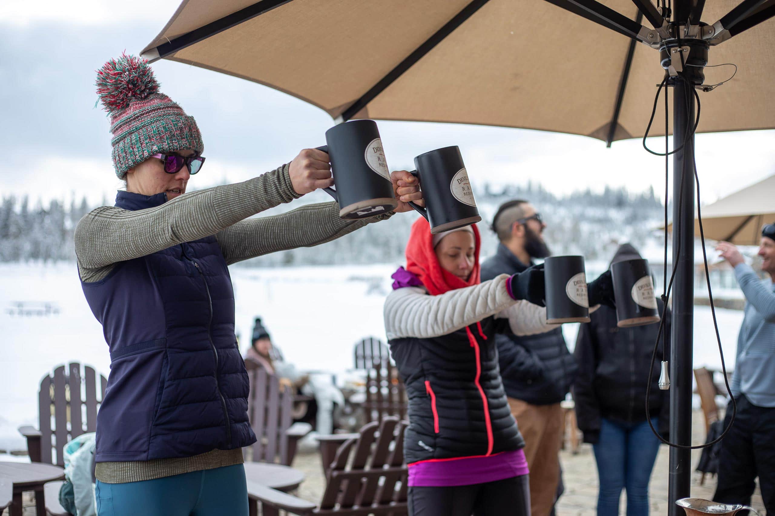 People enjoying hot beverages outdoors at Devil's Thumb Ranch in winter.