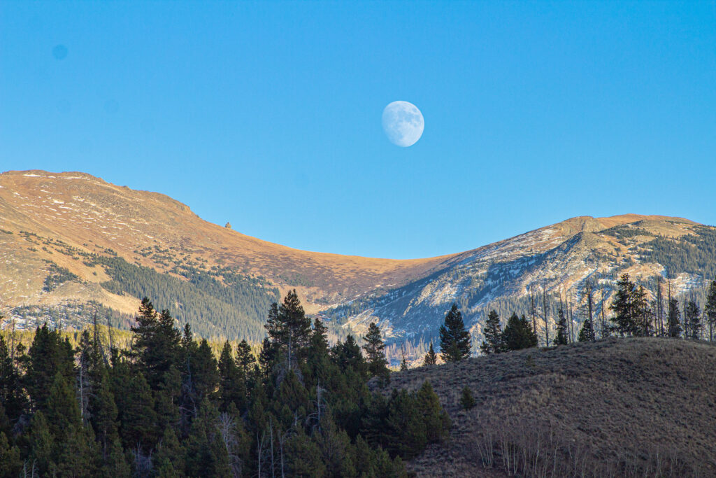 Moon rises over the Continental Divide mountains and the Devil's Thumb geological landmark